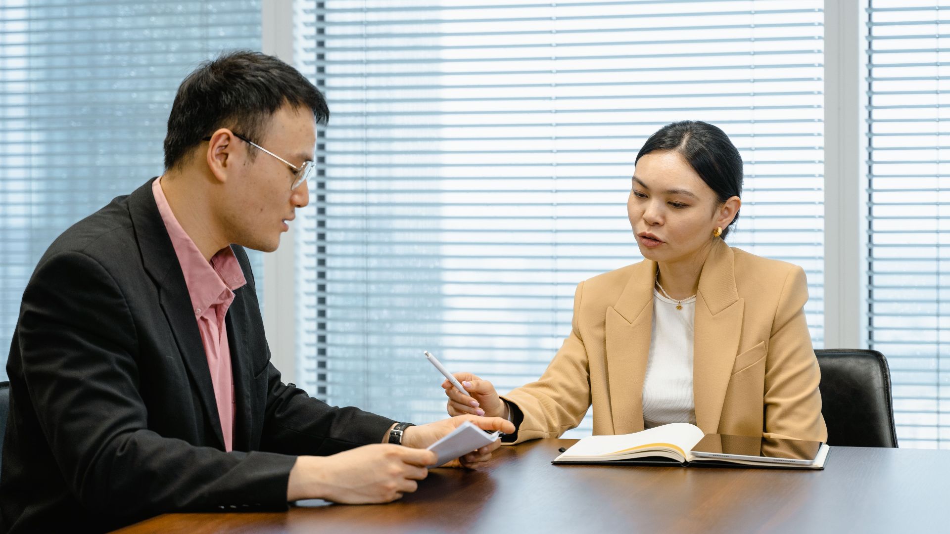 Two business professionals engaged in a collaborative meeting in a modern office setting.
