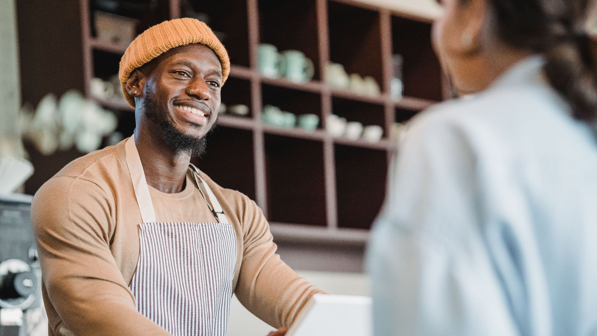 A smiling barista taking an order from a customer at a café counter, creating a warm atmosphere.