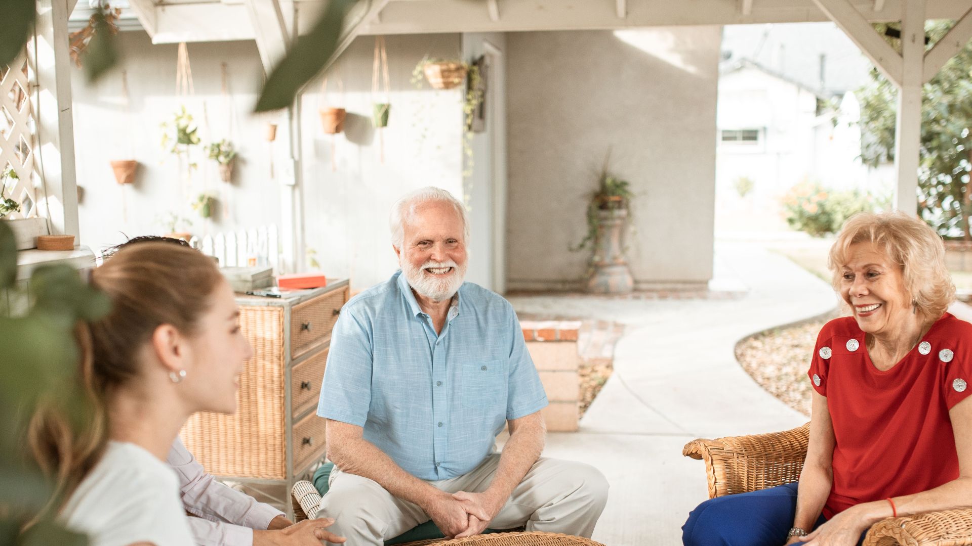Family enjoying a relaxed conversation on a cozy outdoor patio with natural light.