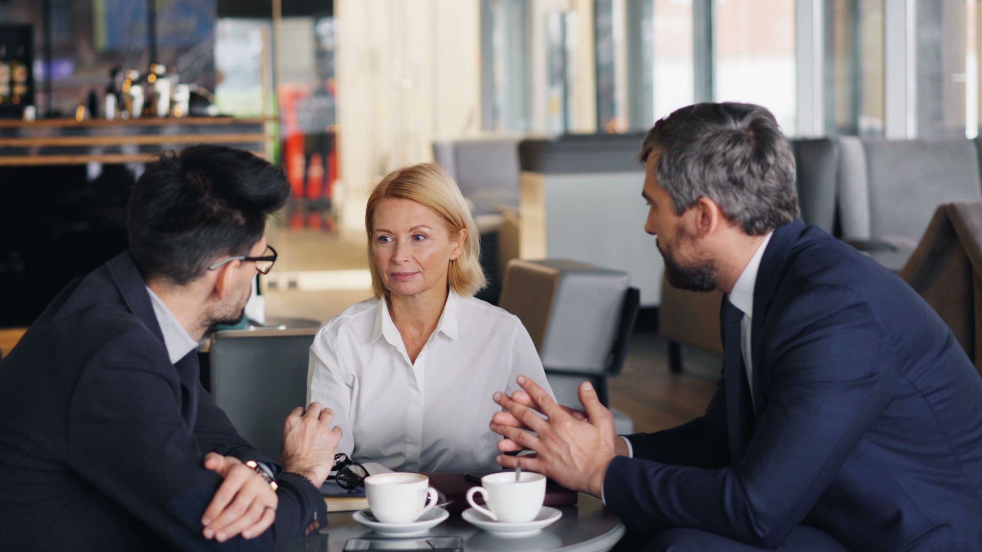 Business professionals engaged in a meeting at a café setting, discussing ideas.