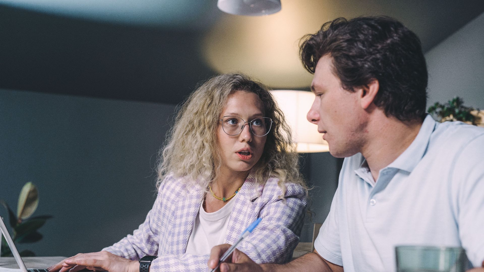 Two coworkers engaged in a focused discussion at a modern office setting.