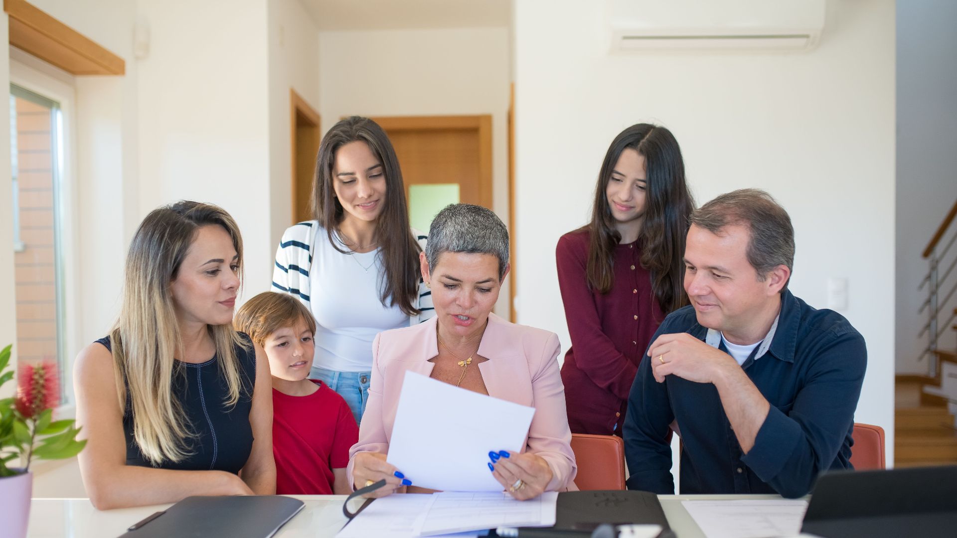 A family meeting with a female realtor reviewing documents in a bright, modern room.