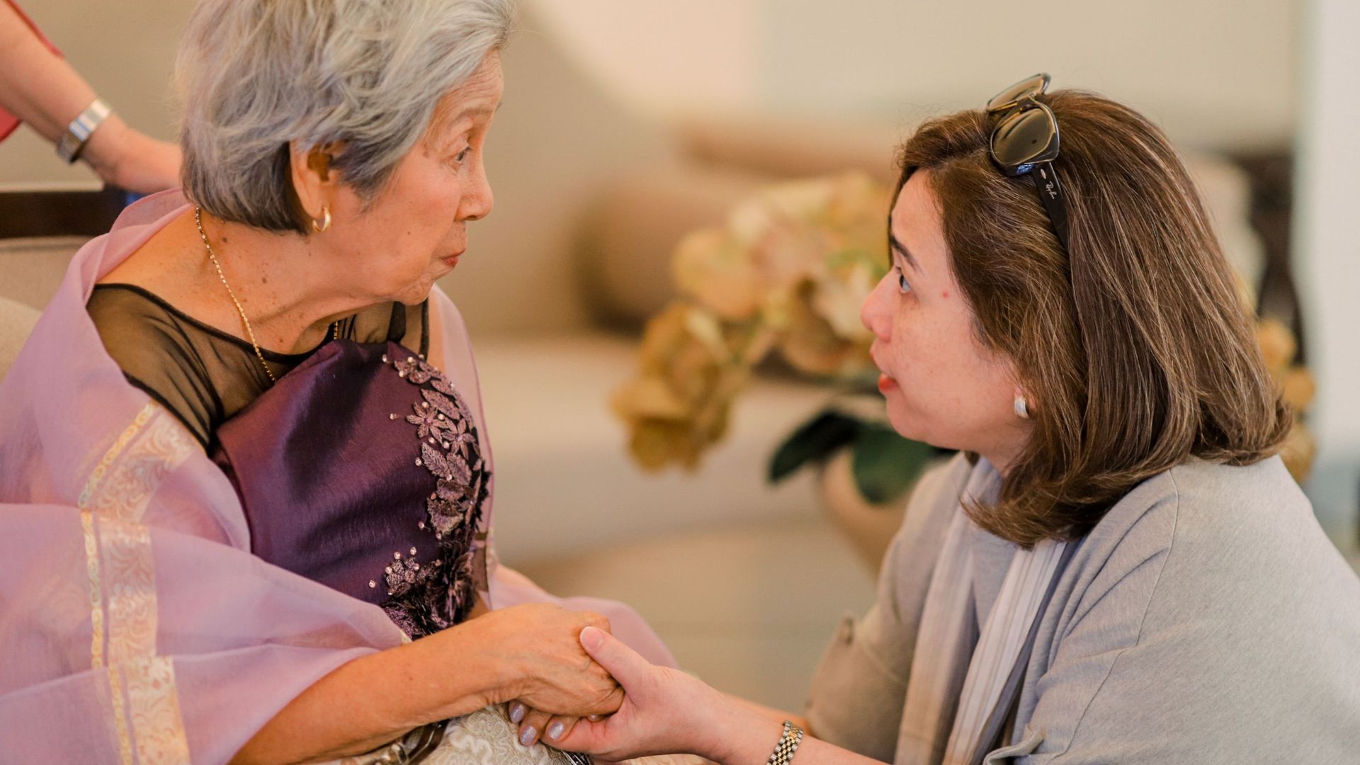 Heartwarming interaction between a senior woman and her adult daughter indoors.