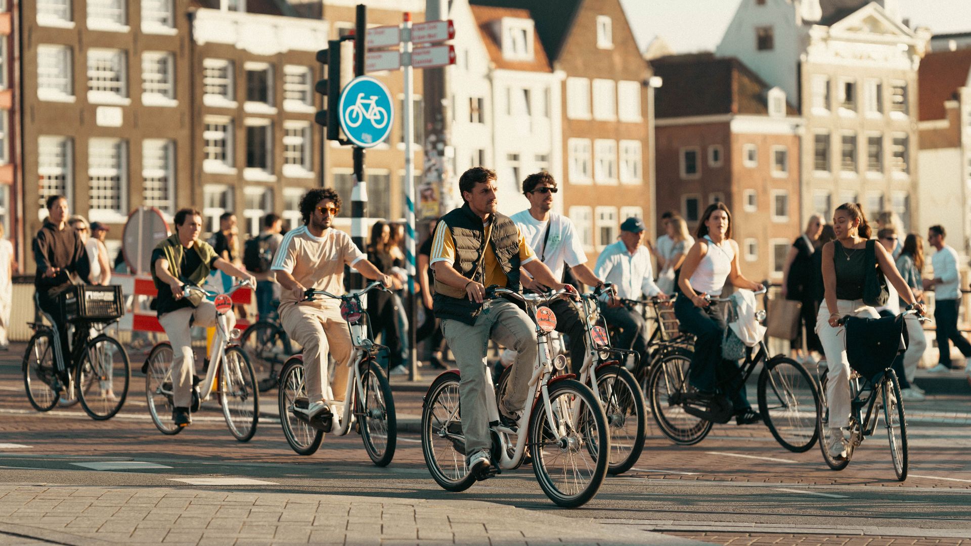A bustling scene of people cycling in Amsterdam. Classic Dutch architecture in the background.