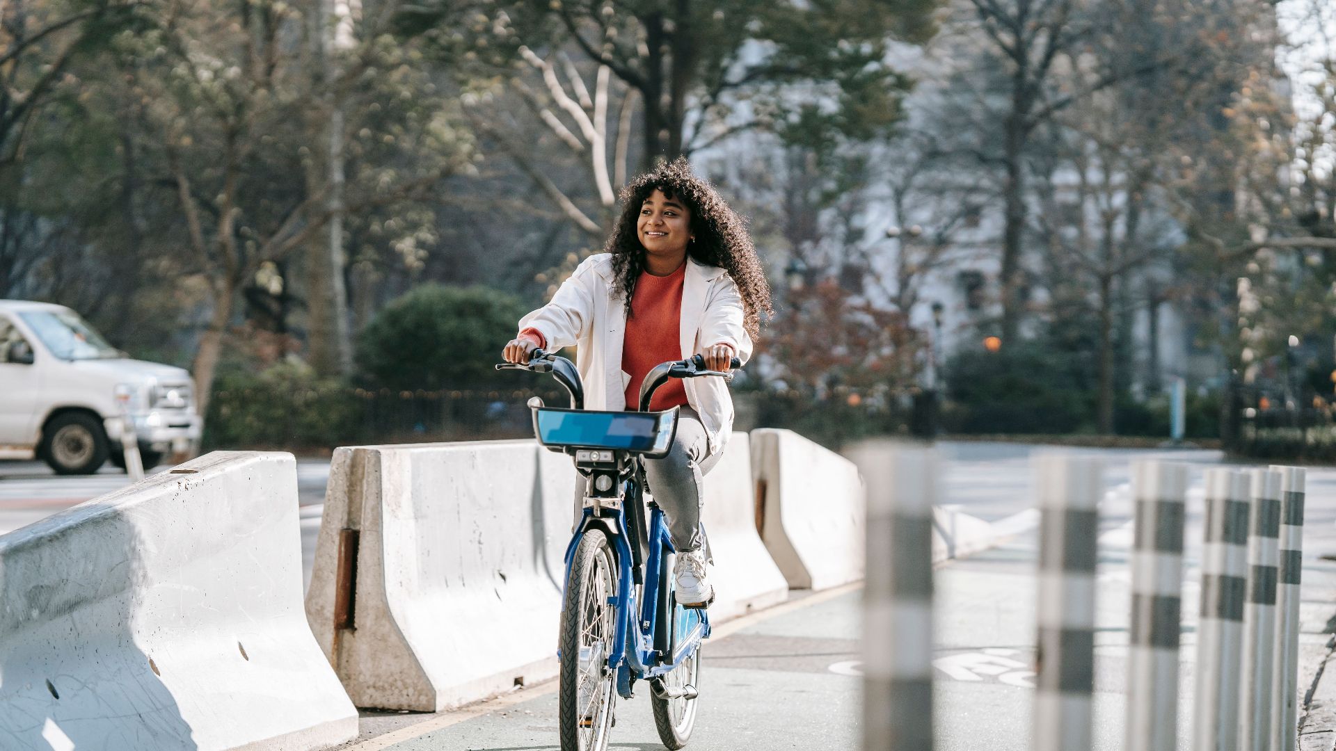 Full body content African American female wearing casual outfit riding bicycle on wet asphalt road in modern street in daylight
