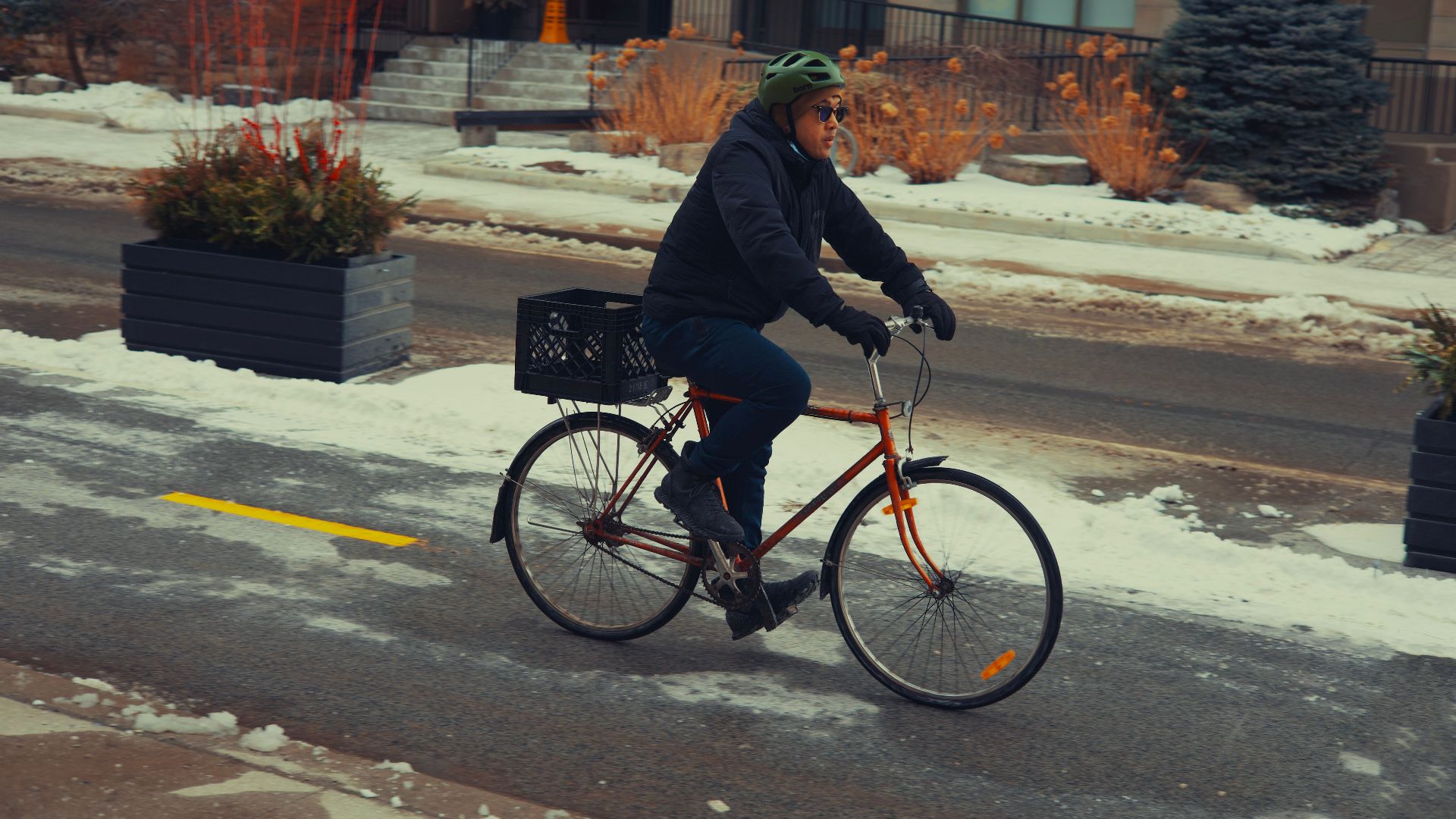A person rides a bicycle on a snowy street in Toronto, ON, showcasing winter urban cycling.