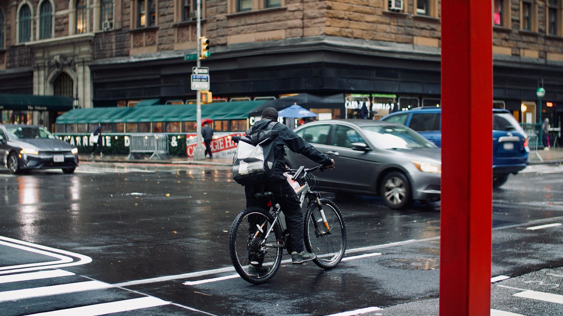 Cyclist navigating a rainy intersection in New York City, showcasing urban life and transportation.