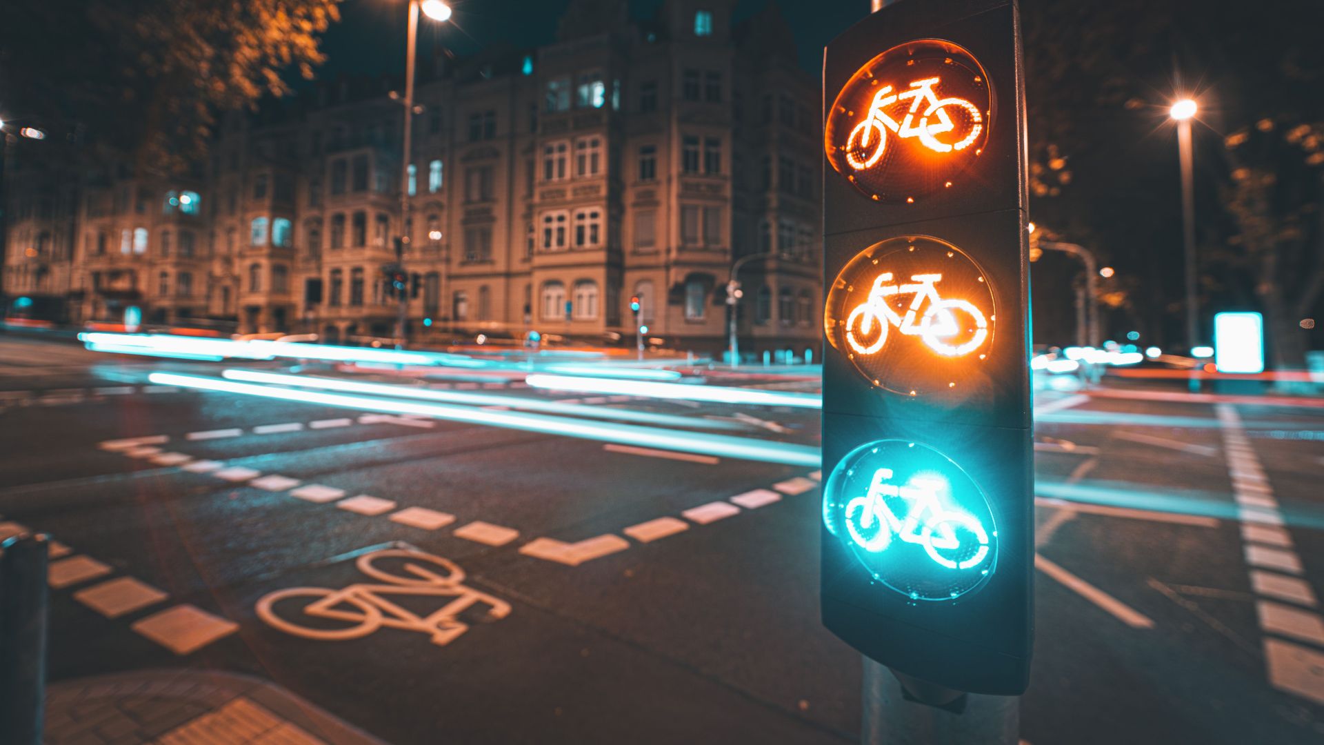 Bicycle traffic light at night with long exposure city lights and classic architecture.