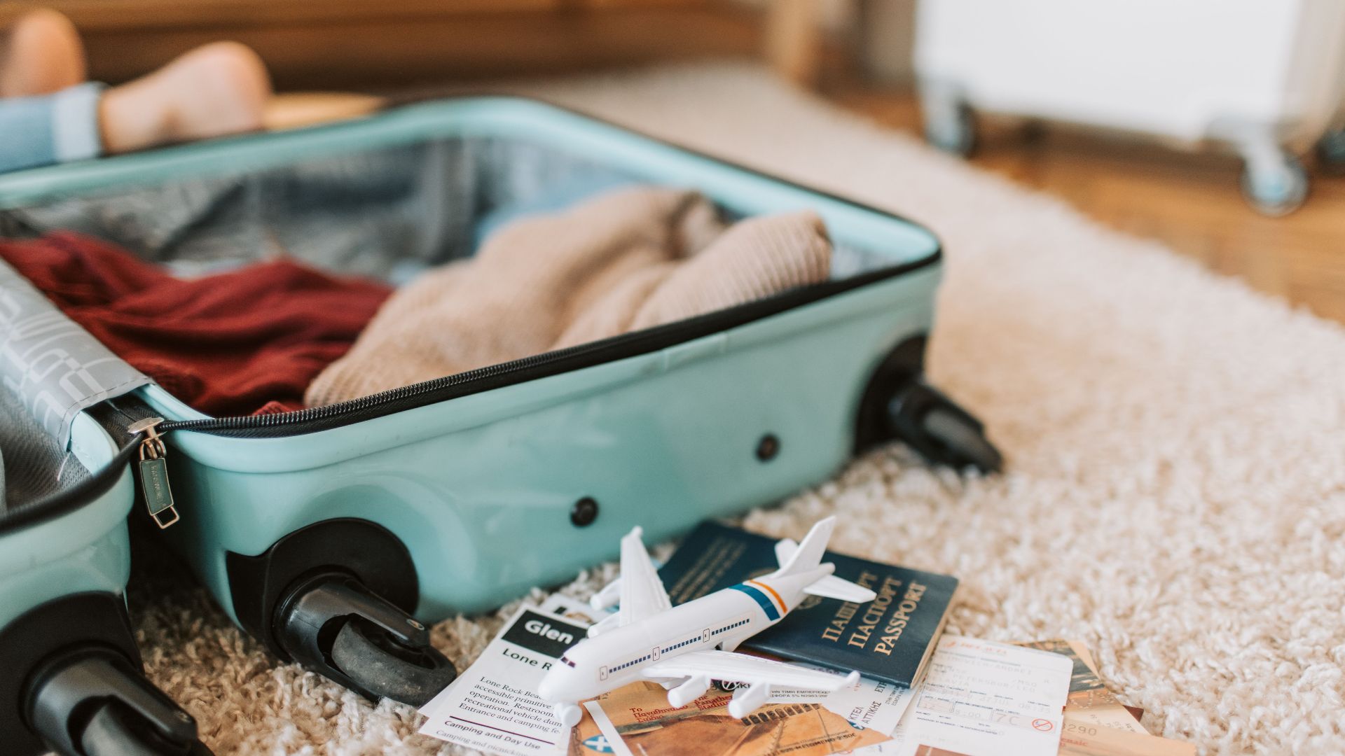 Close-up of an open suitcase with travel essentials like passport and tickets, ready for a journey.