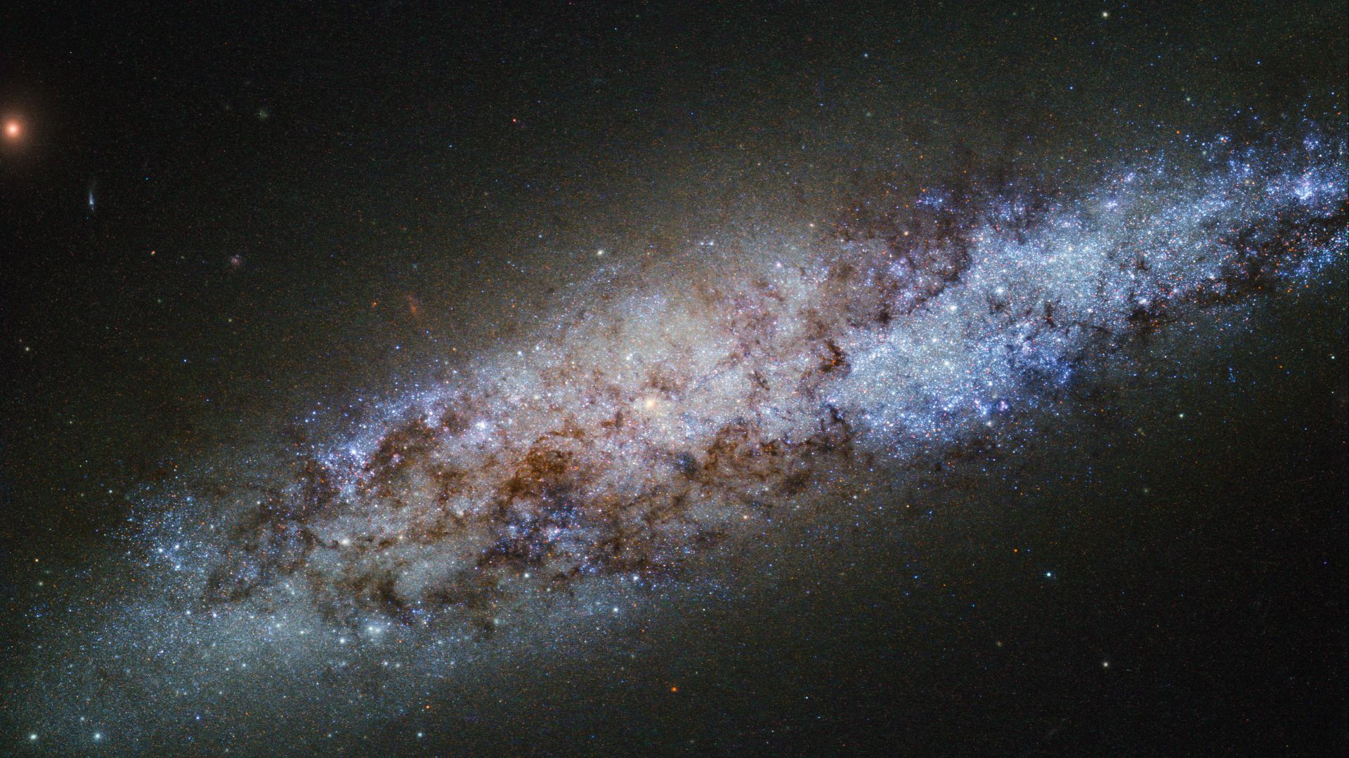 This bundle of bright stars and dark dust is a dwarf spiral galaxy known as NGC 4605, located around 16 million light-years away in the constellation of Ursa Major (The Great Bear). This galaxy’s spiral structure is not obvious from this image, but NGC 46
