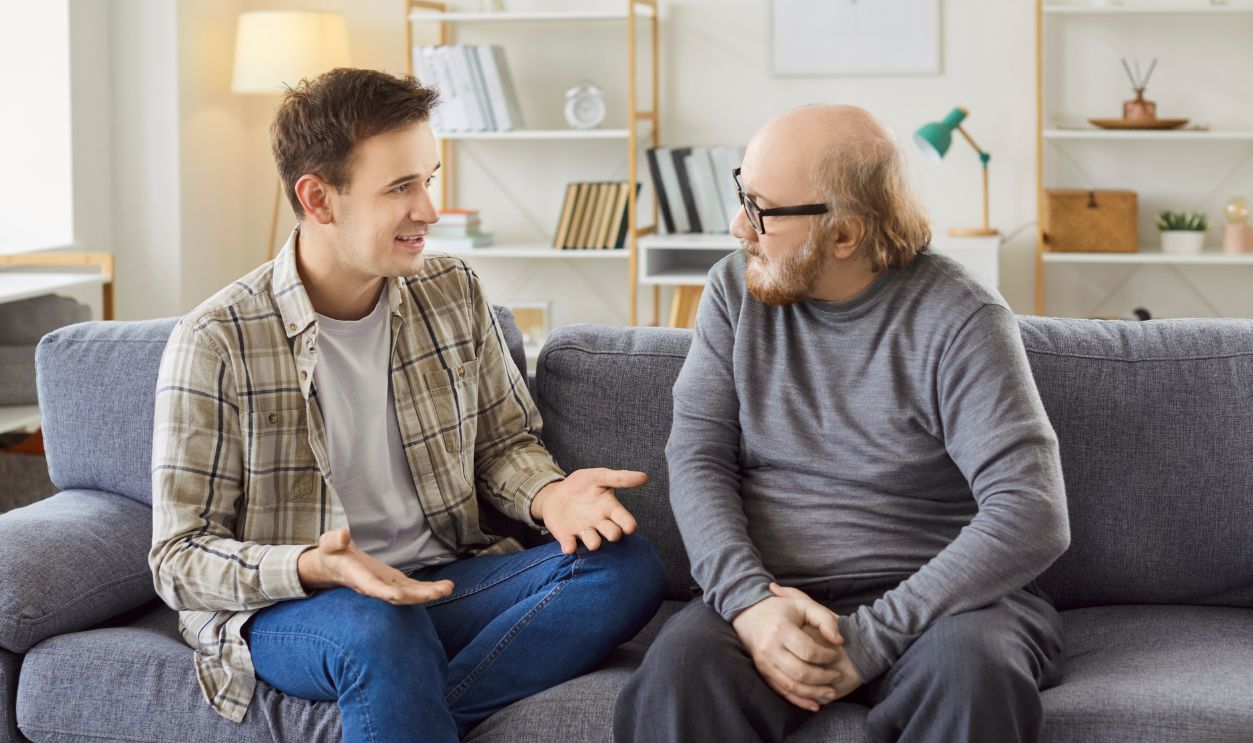 Shutterstock-2652261241, Adult son and a senior father talking. Old man in his 60s sitting on the couch together with his grown up son and listening to him ready to share his life wisdom. Parents and children concept