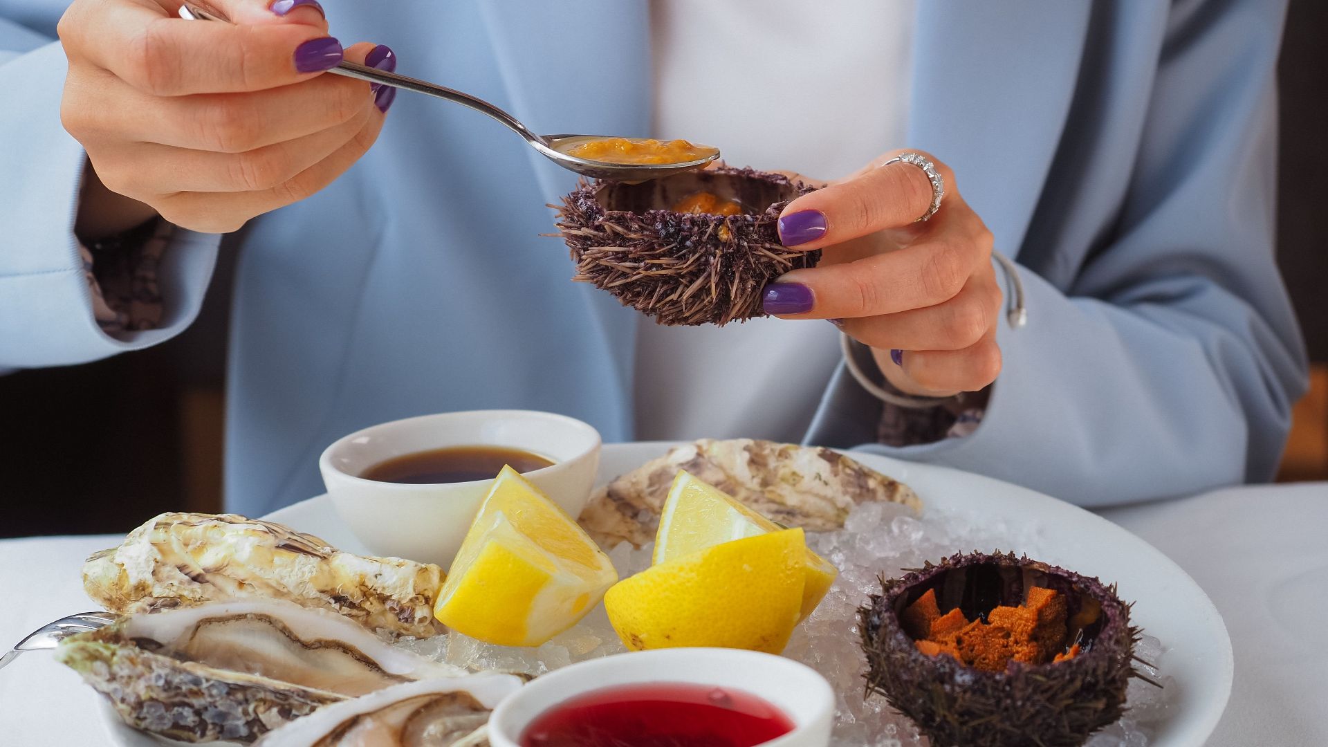 Close-up of a seafood platter with fresh oysters and lemon wedges in a fine dining setting.