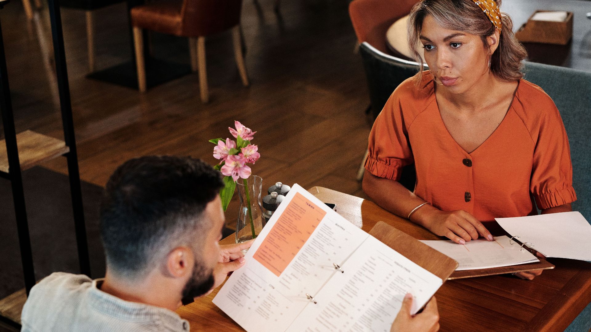 A couple sitting indoors at a café, reviewing a menu for a casual dining experience.