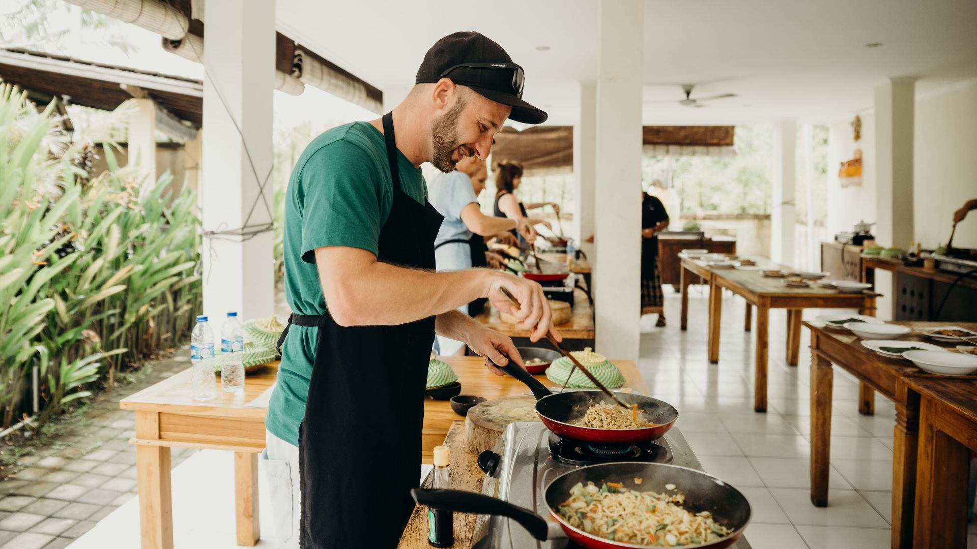 A chef prepares a meal in an open-air kitchen setting in Bali, Indonesia.