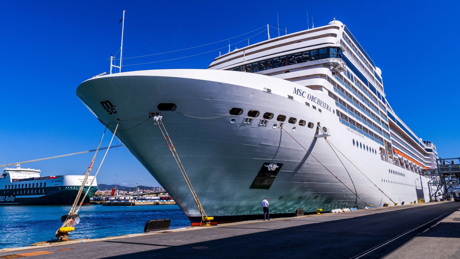 A large cruise ship docked at Barcelona port under a clear blue sky, showcasing maritime travel.