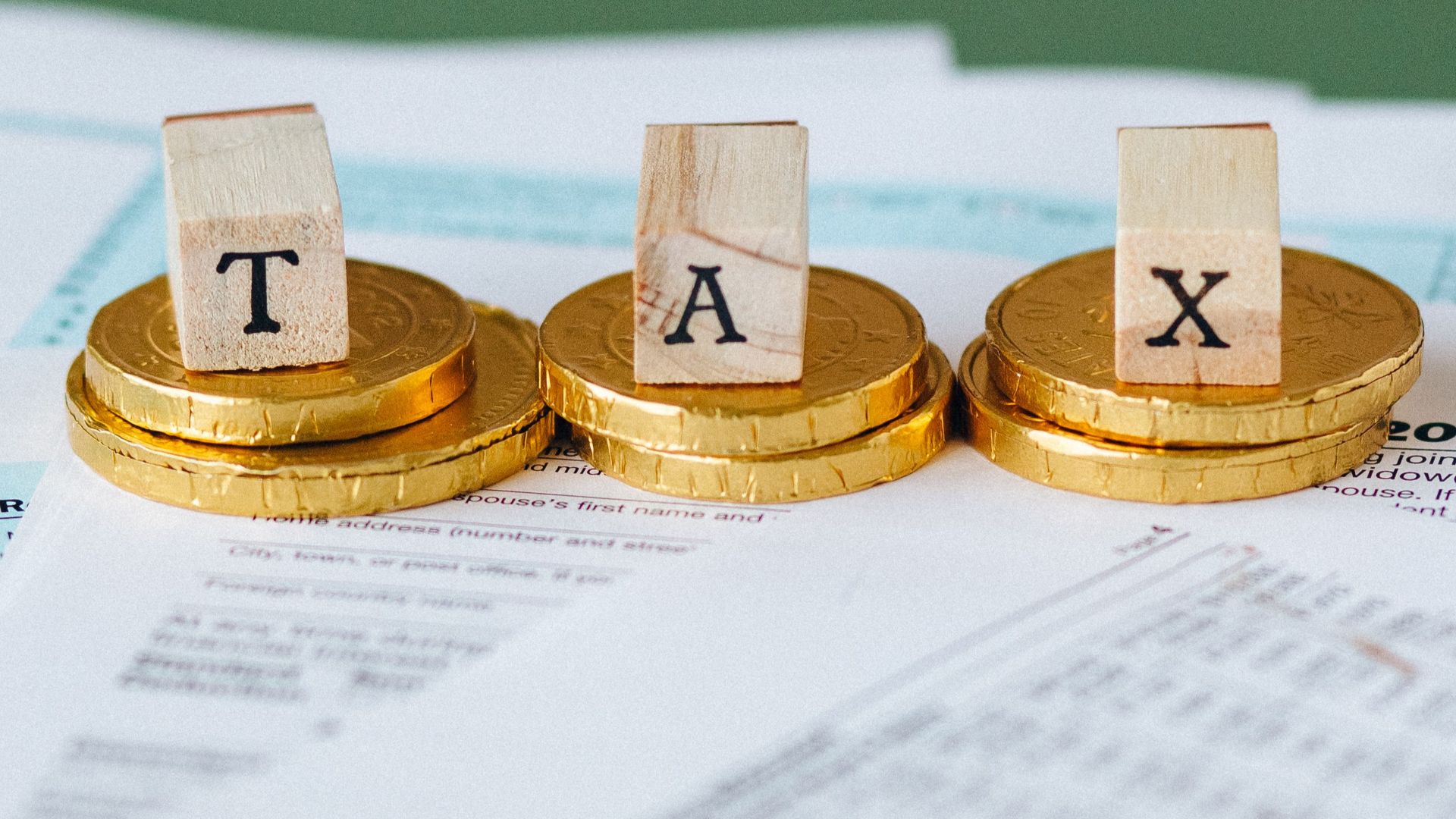 Staged image of gold coins with tax letter tiles on documents.