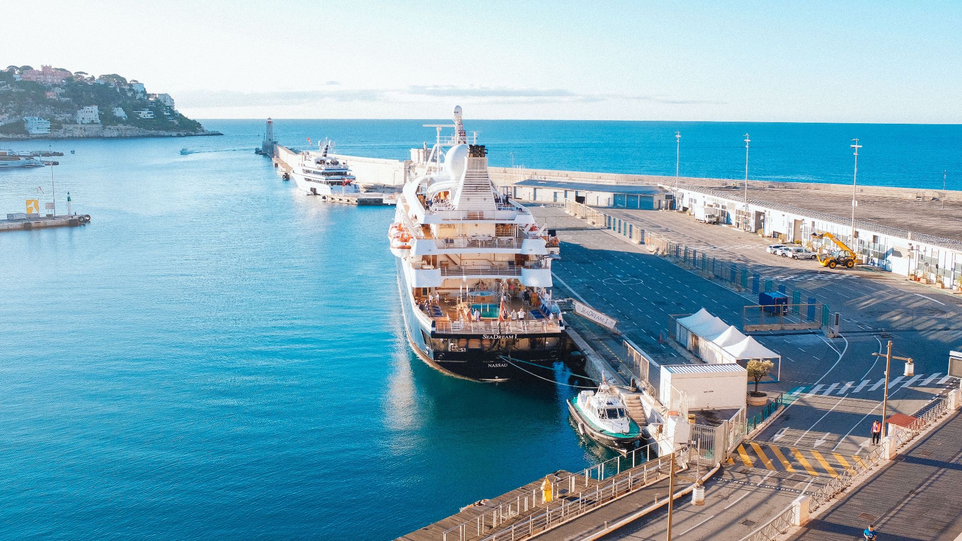 Aerial view of a cruise ship docked at a scenic port, showcasing a vibrant blue sea and clear sky.