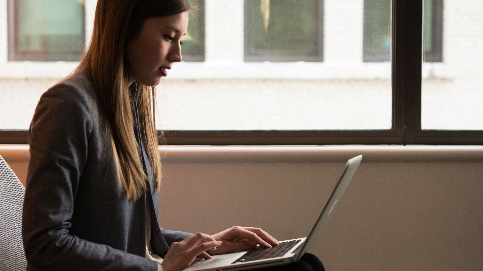 Professional woman using laptop in modern indoor setting. Ideal for business or technology themes.