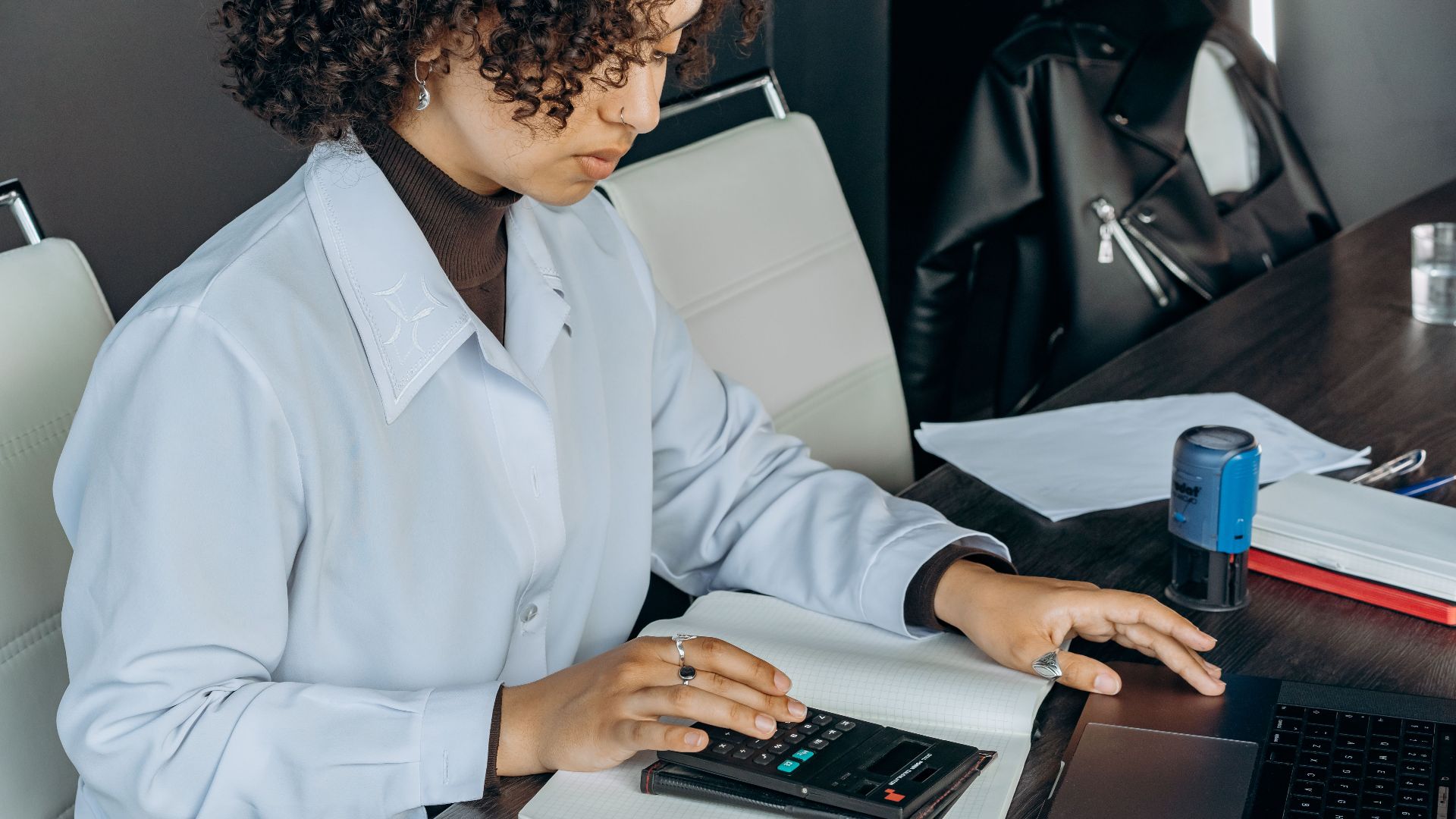Young woman in office using a calculator for financial calculations.