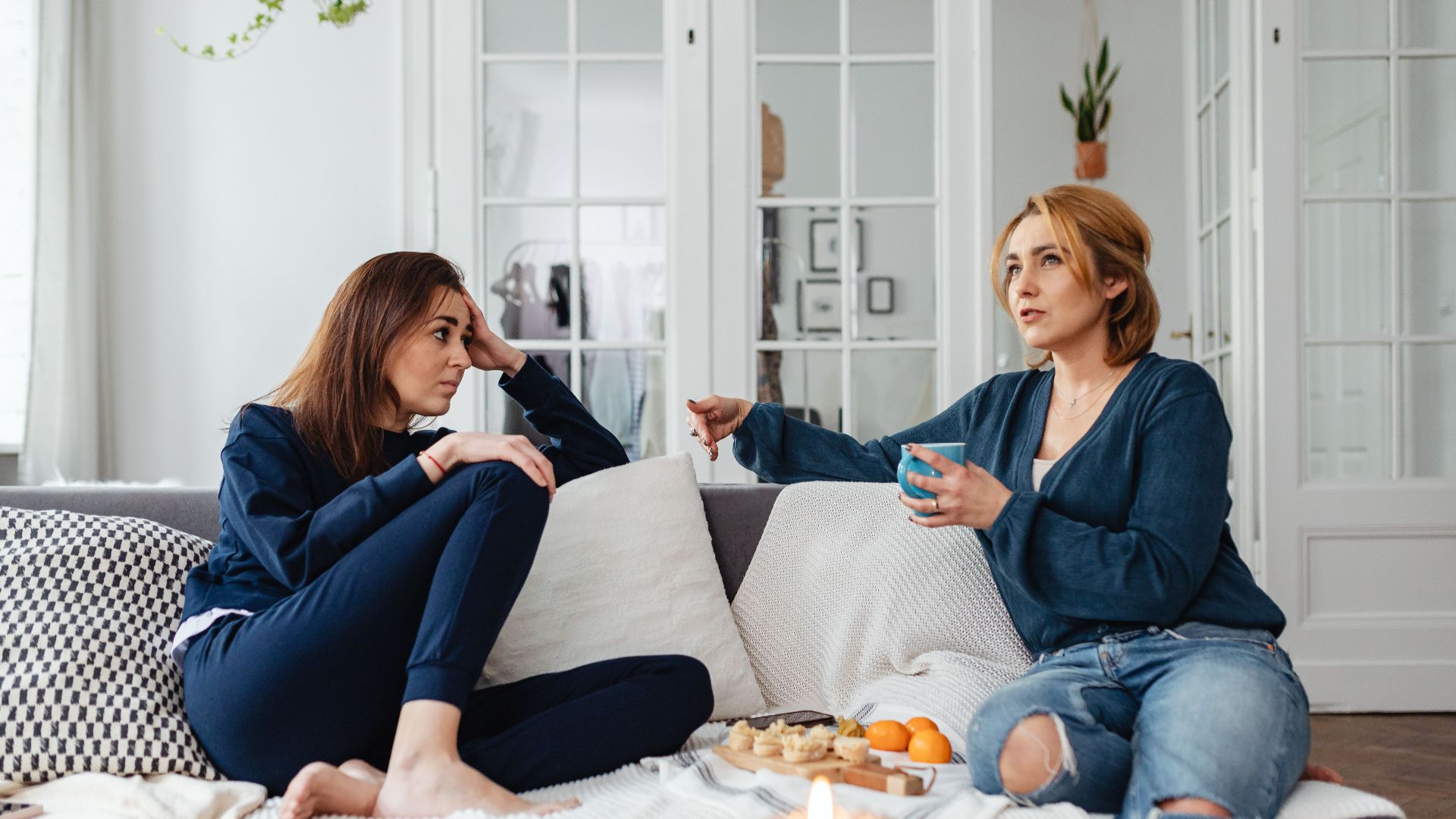 Casual conversation between two women indoors on a comfortable sofa.