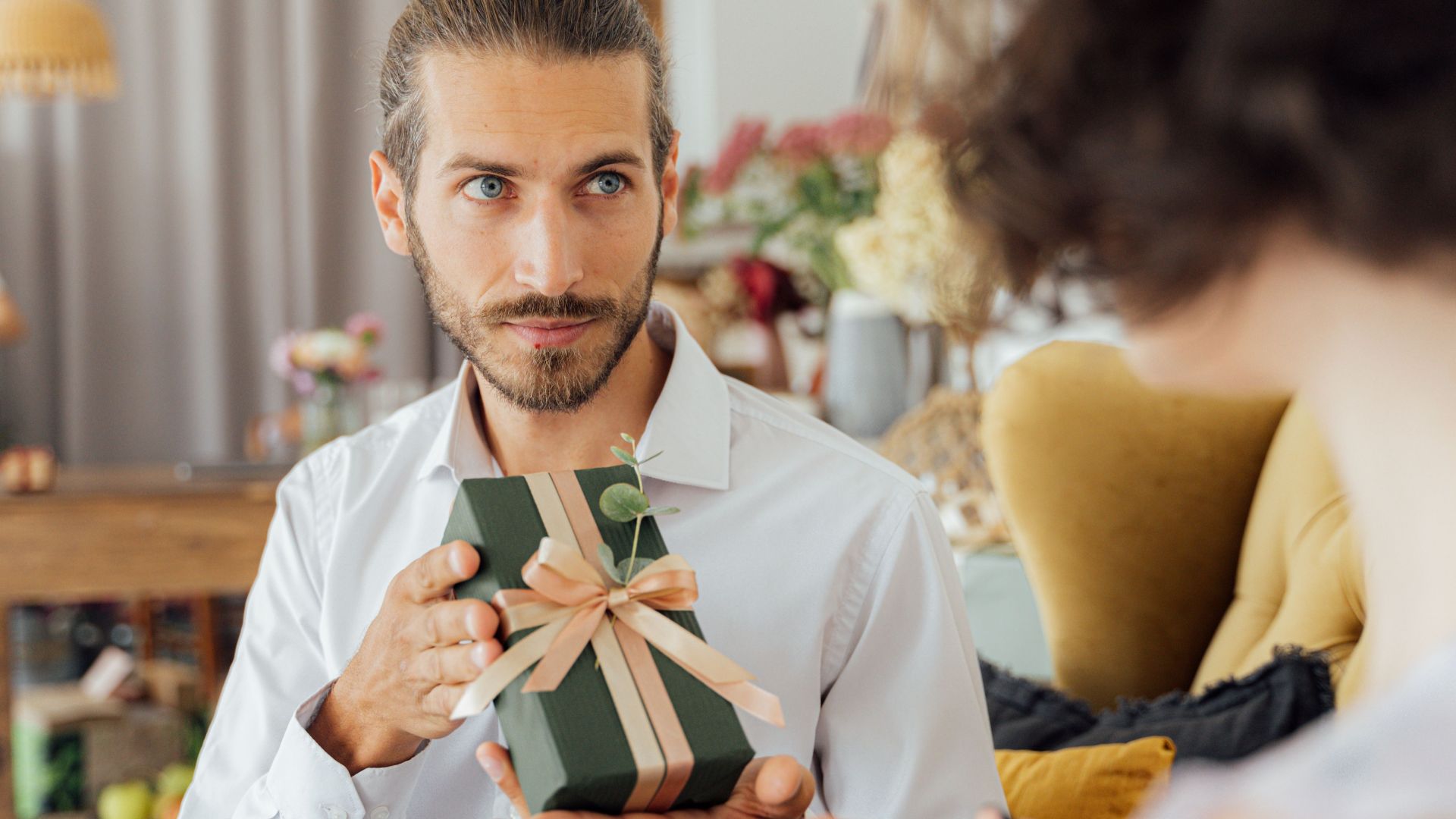 A thoughtful moment captured as a man presents a gift in a cozy indoor setting.