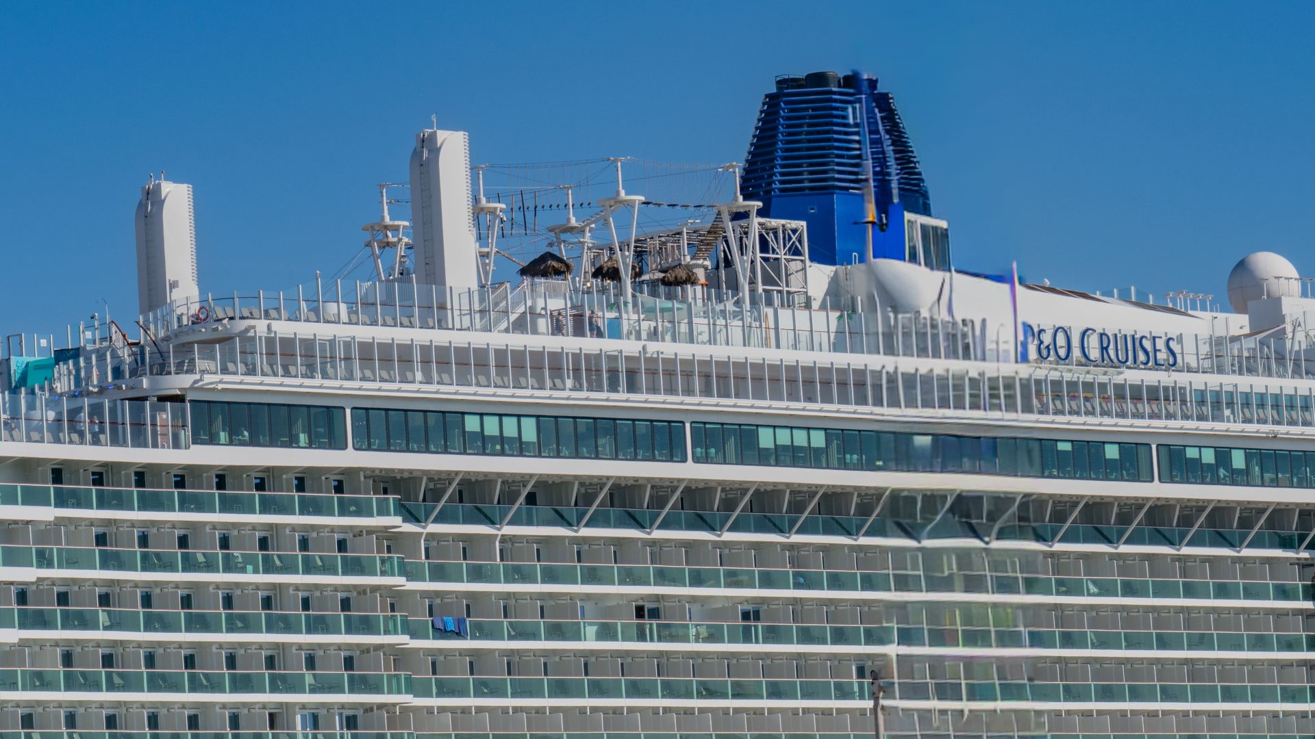 Close-up of a modern cruise ship docked in Cádiz, Spain under a clear blue sky.