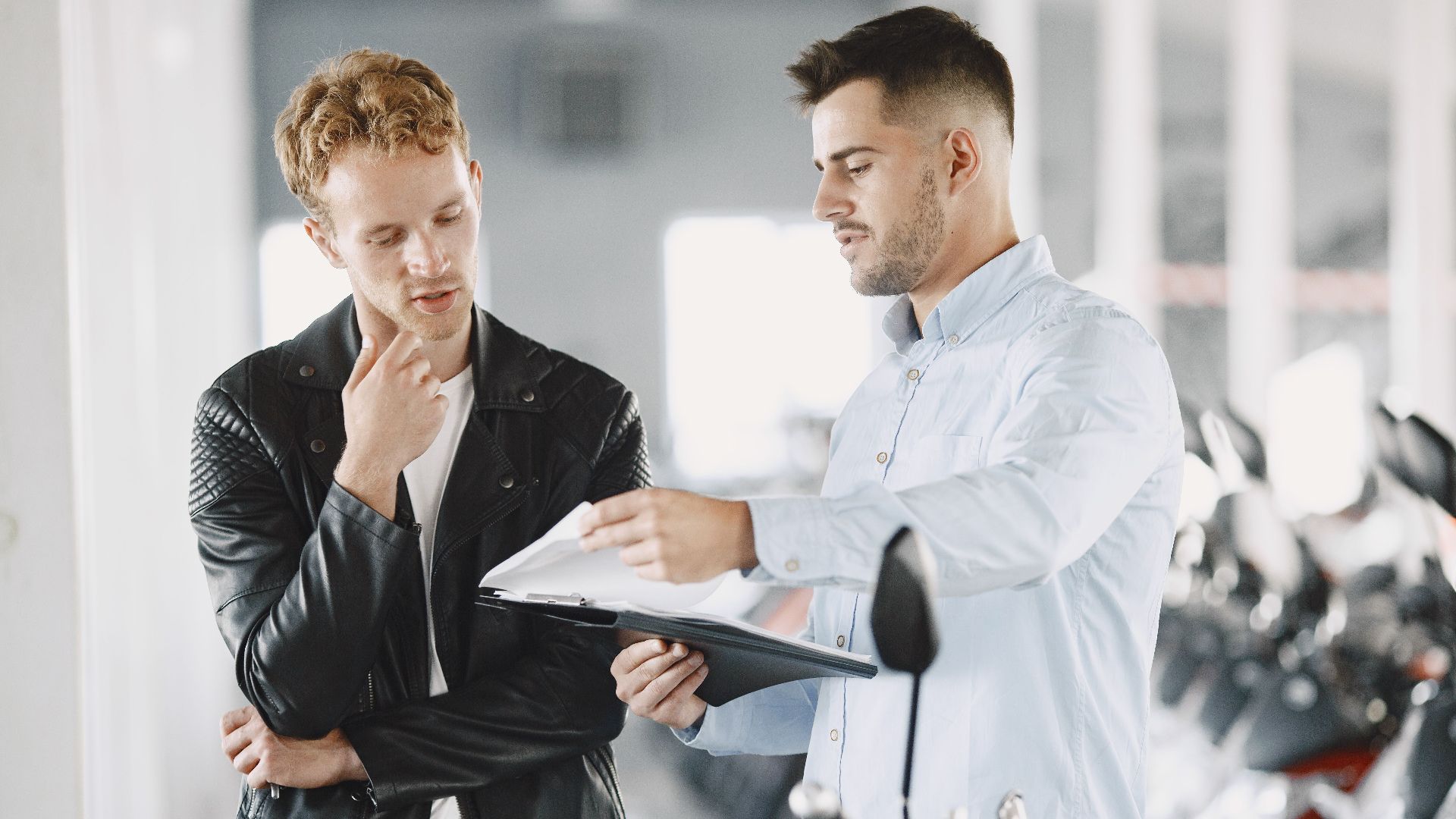 Two adults discussing purchasing options at a motorcycle dealership.