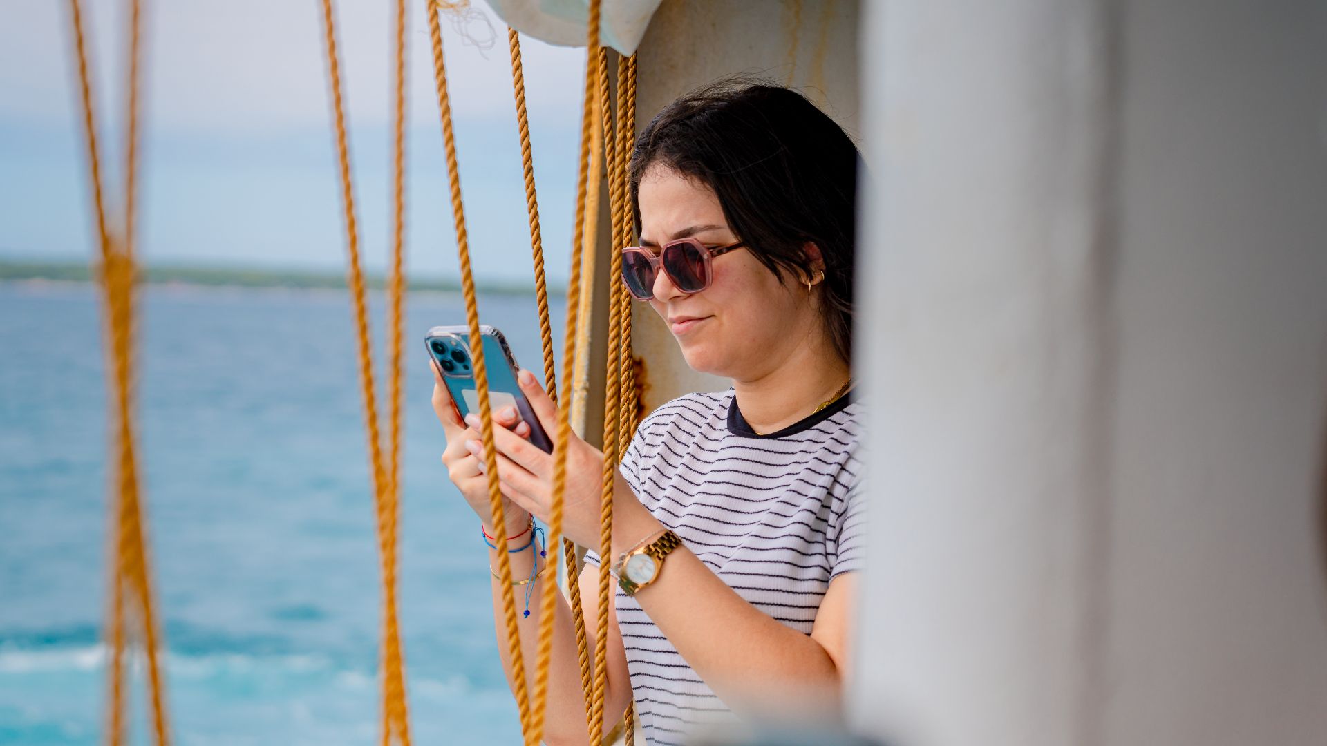A young woman uses her smartphone while enjoying the ocean view from a boat in San Remigio, Philippines.