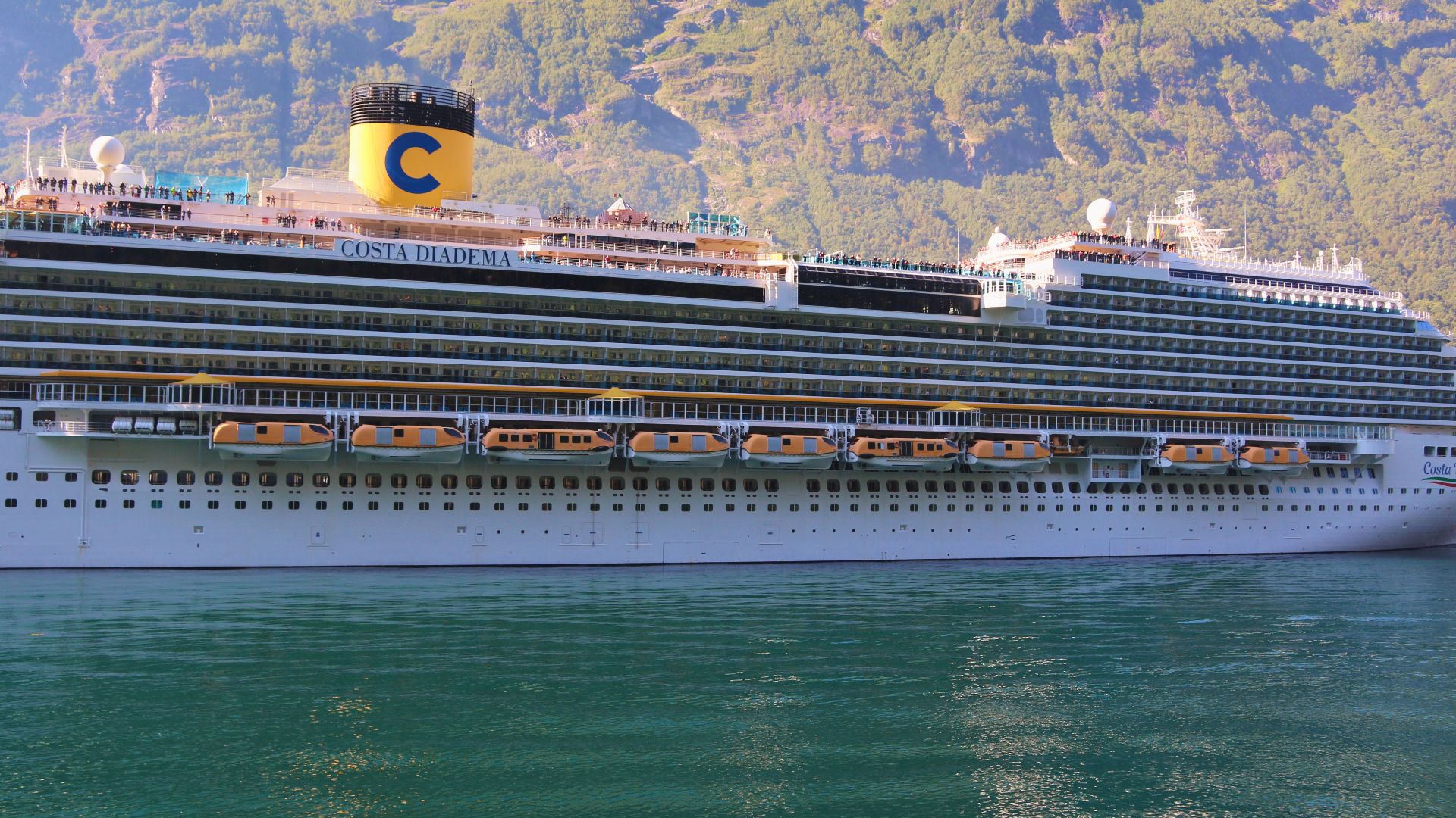 Scenic view of a cruise ship in a Norwegian fjord with green mountains.