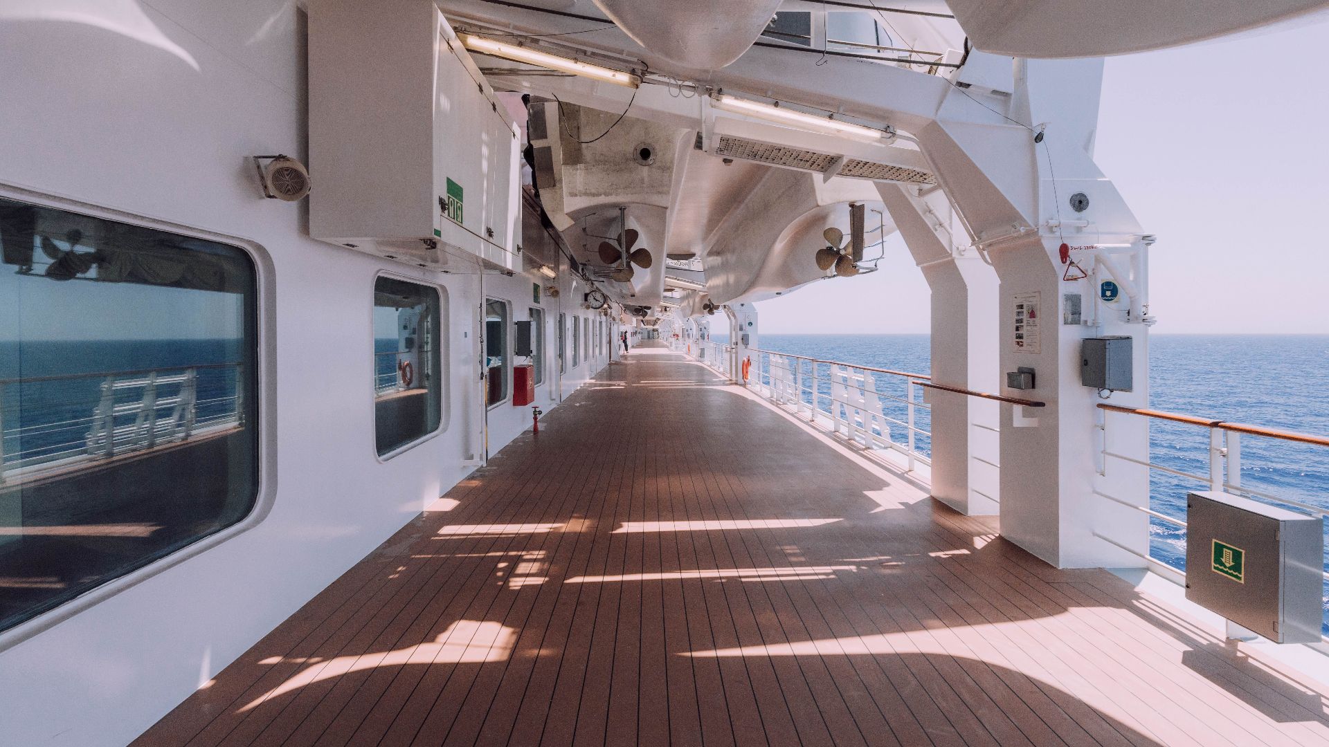 Spacious cruise ship deck overlooking the serene ocean under a clear sky.