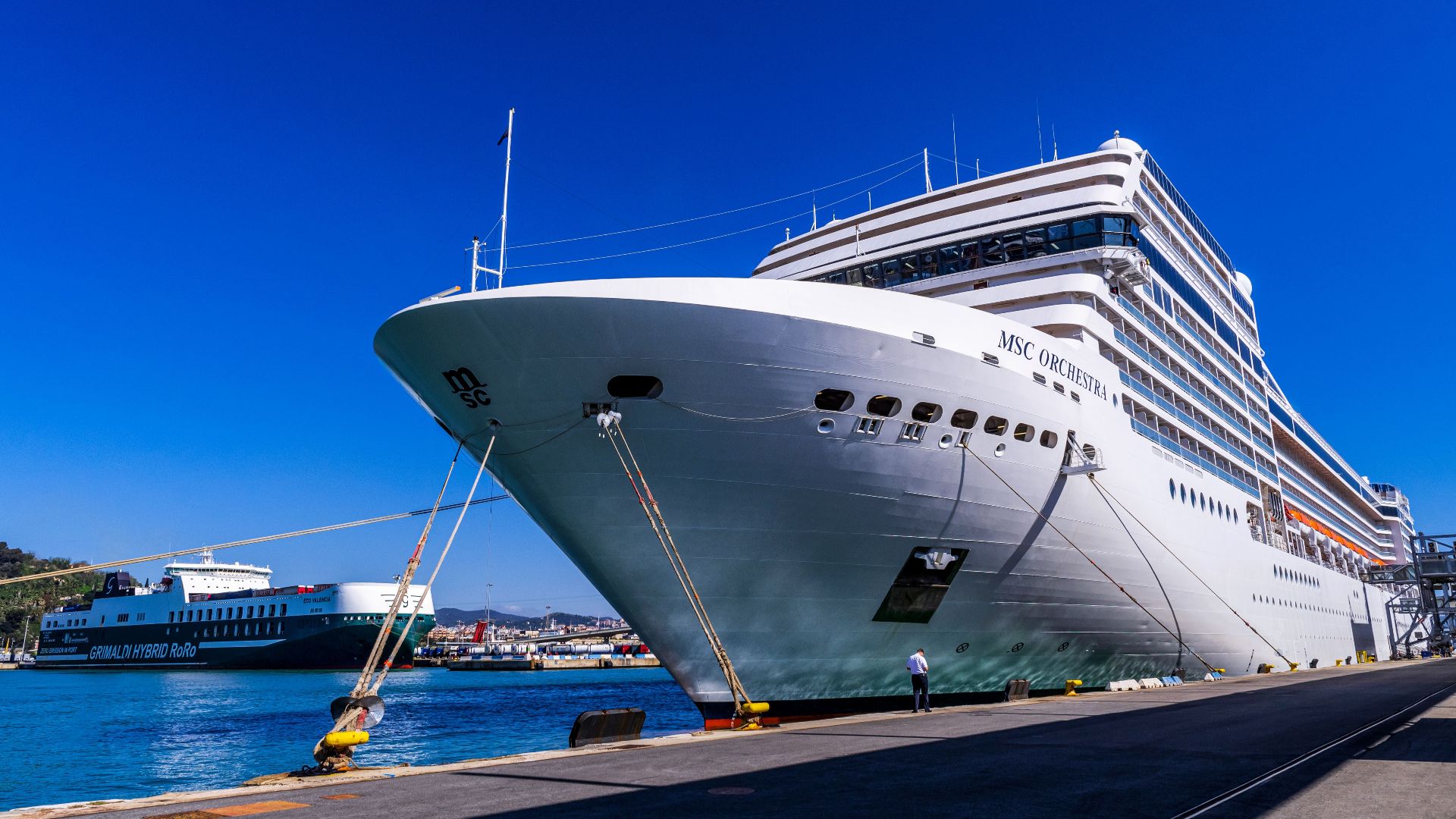 A large cruise ship docked at Barcelona port under a clear blue sky, showcasing maritime travel.