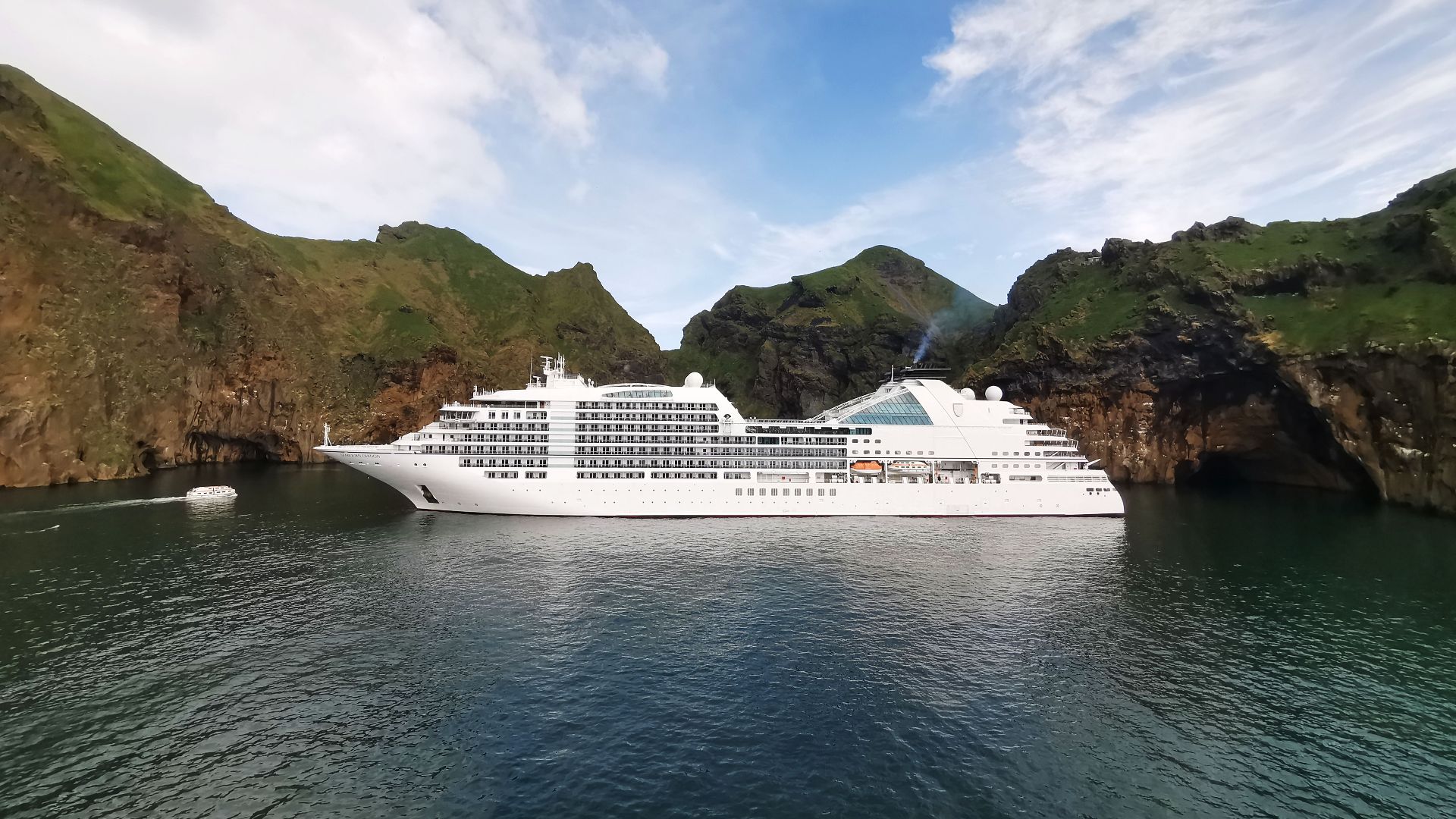A stunning view of a luxury cruise ship in a picturesque Icelandic cove surrounded by cliffs.
