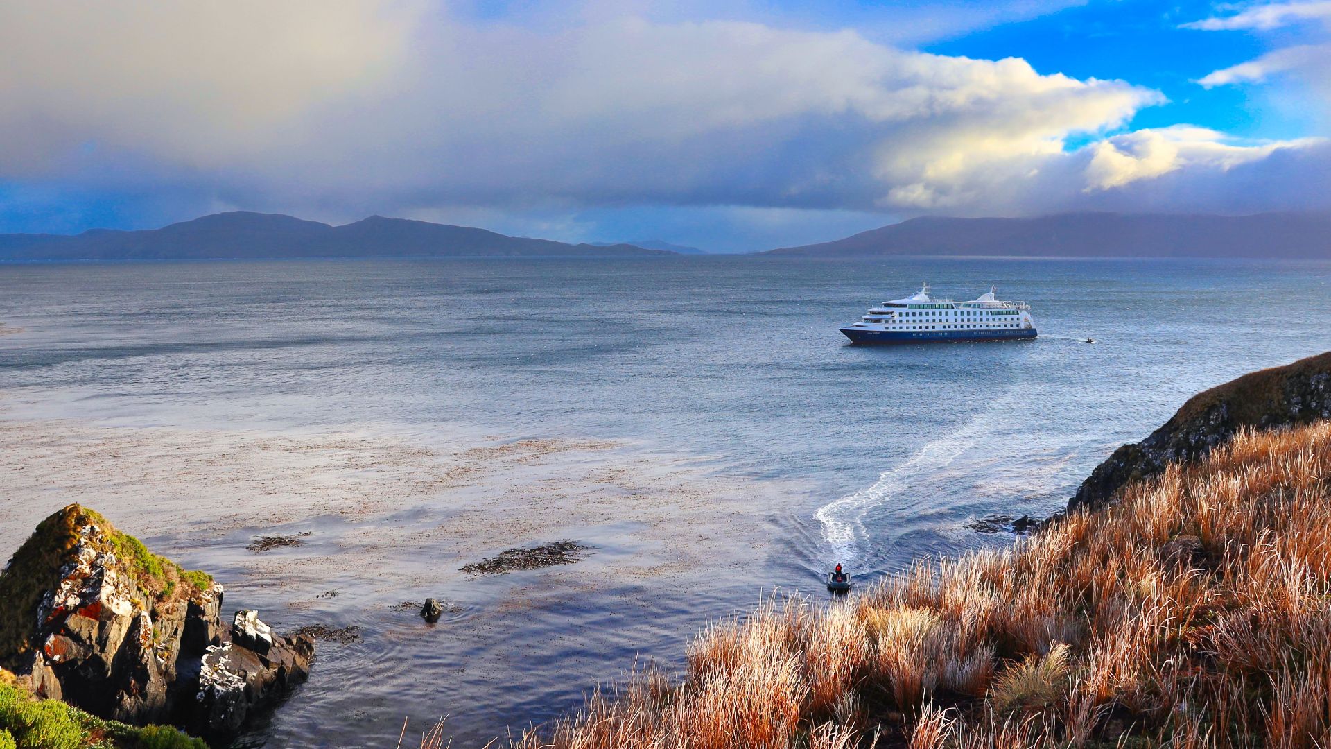 Picturesque cruise ship sailing near Cape Horn, Chile under dramatic skies.