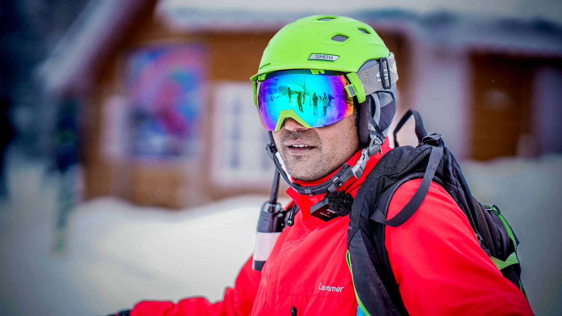 Adult skier wearing bright gear and reflective goggles, enjoying a snowy outdoor scene.