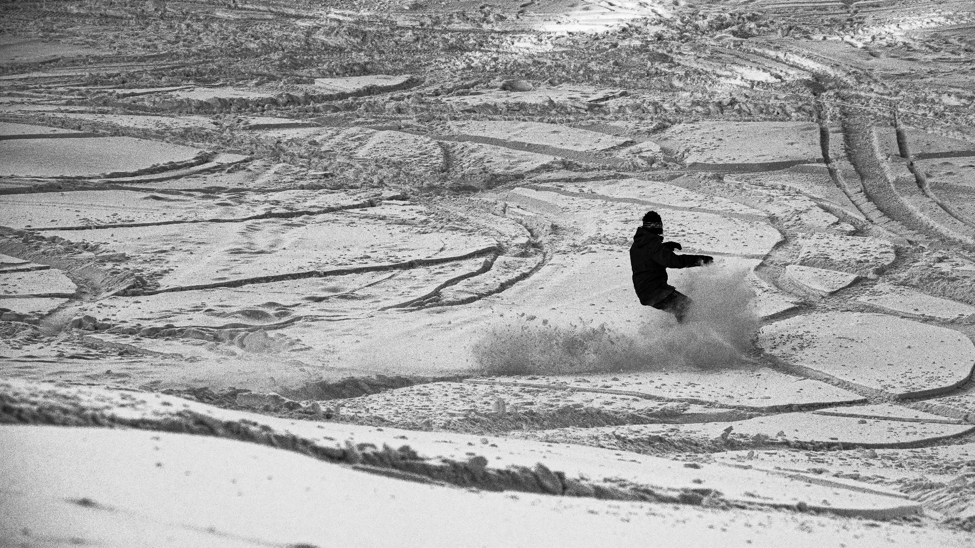 A snowboarder skillfully carves through fresh snow on a winter day, capturing the thrill of the sport.