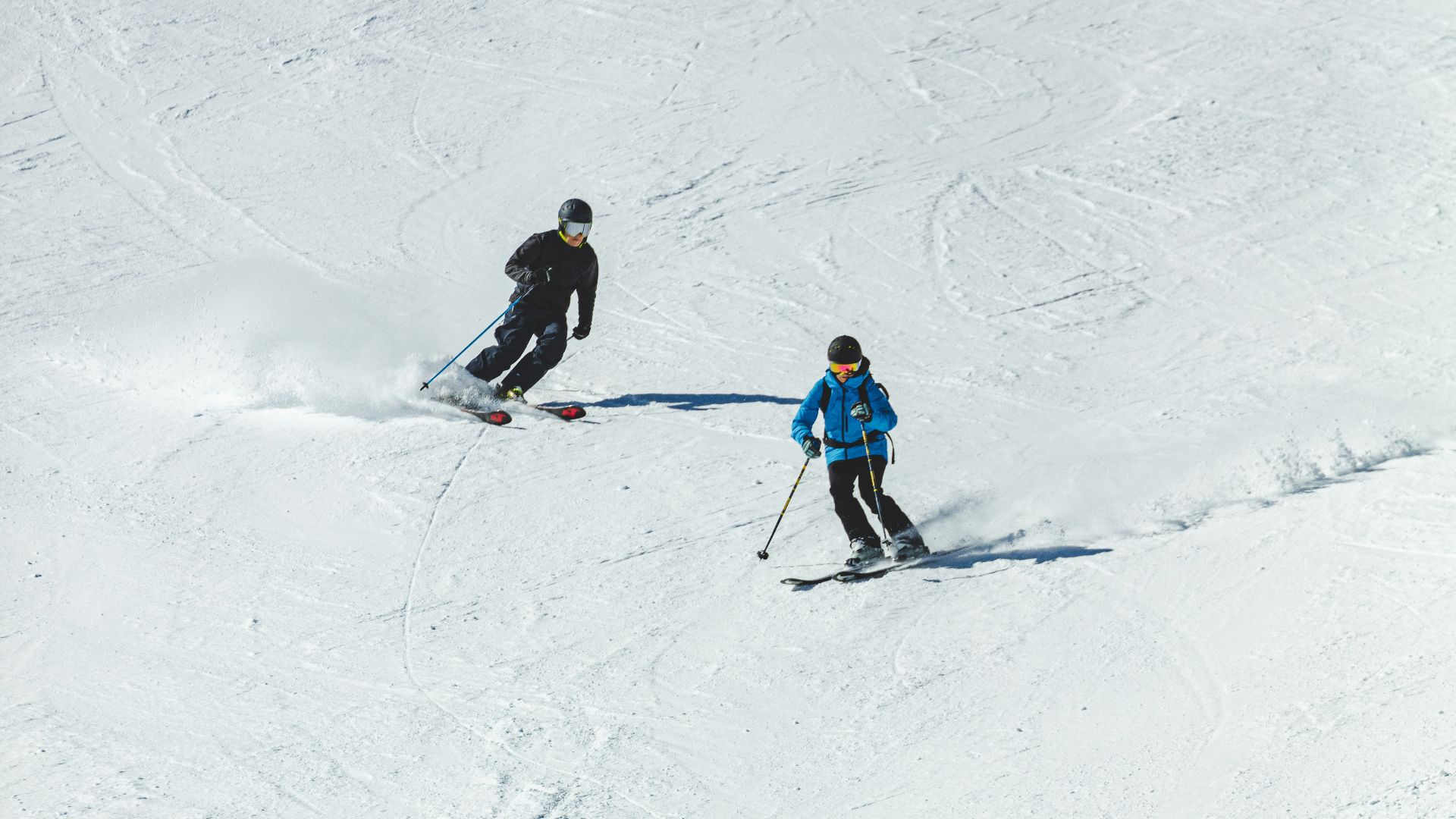 person in blue jacket and black pants riding ski blades on snow covered ground during daytime