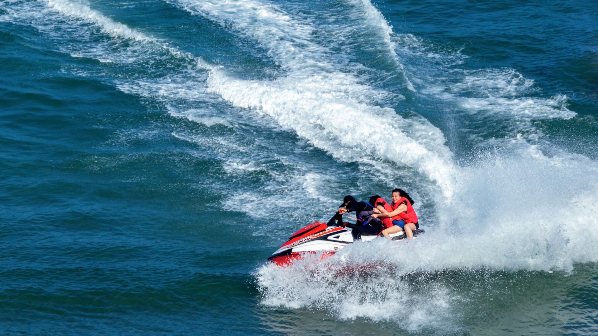Group enjoying a thrilling jet ski ride on the ocean, creating splashes and waves.