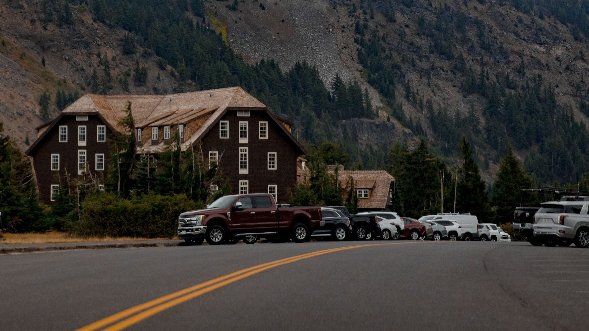 Fog envelops Crater Lake Lodge in Oregon, surrounded by trees and mountains.