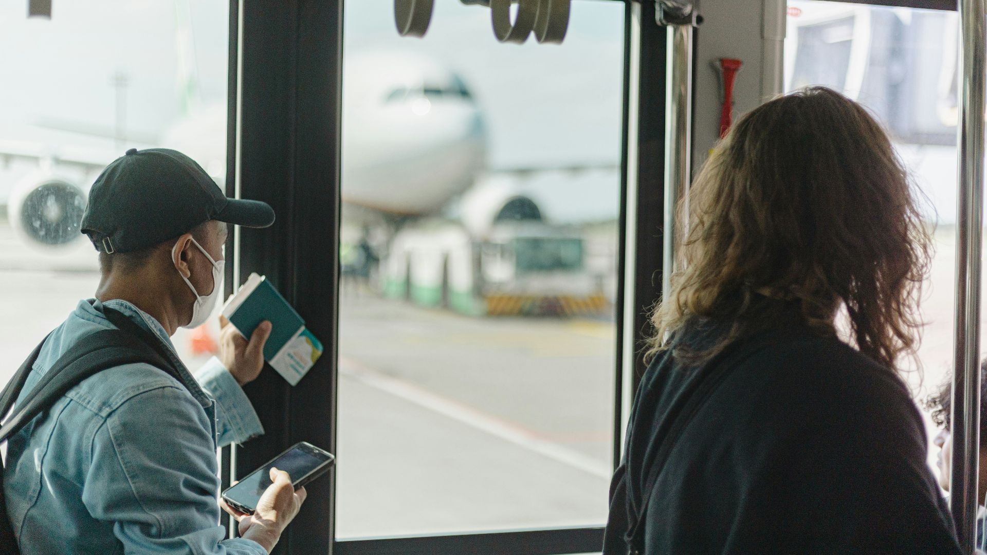 People boarding a bus with airplane visible outside
