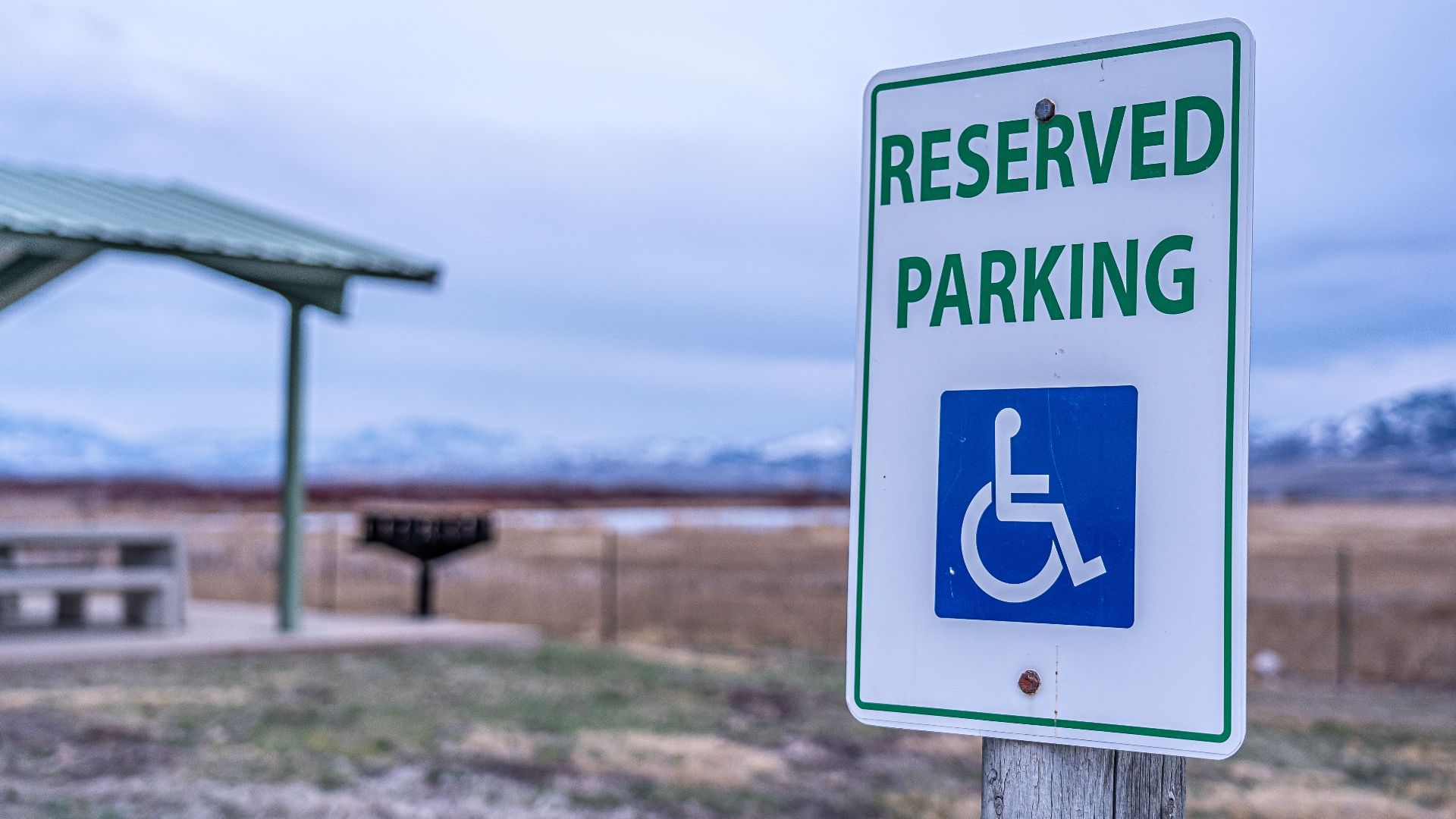 Close-up of a reserved parking sign by a scenic picnic area with distant mountains.