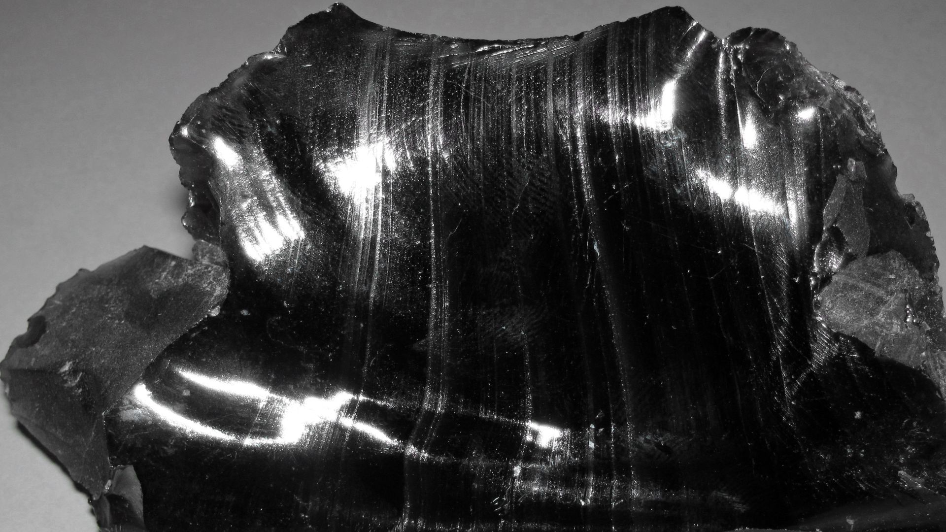 Obsidian is a glassy-textured, extrusive igneous rock.  Obsidian is natural glass - it lacks crystals, and therefore lacks minerals.  Obsidian is typically black in color, but most obsidians have a felsic to intermediate chemistry.  Felsic igneous rocks a