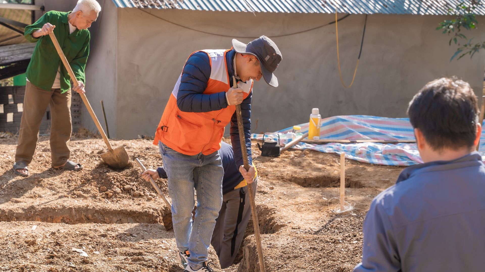 Adults and a senior working together on a construction project outdoors.