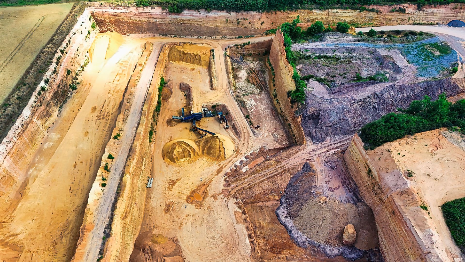 Aerial view of a large sandstone quarry with heavy machinery digging and piles of sand.