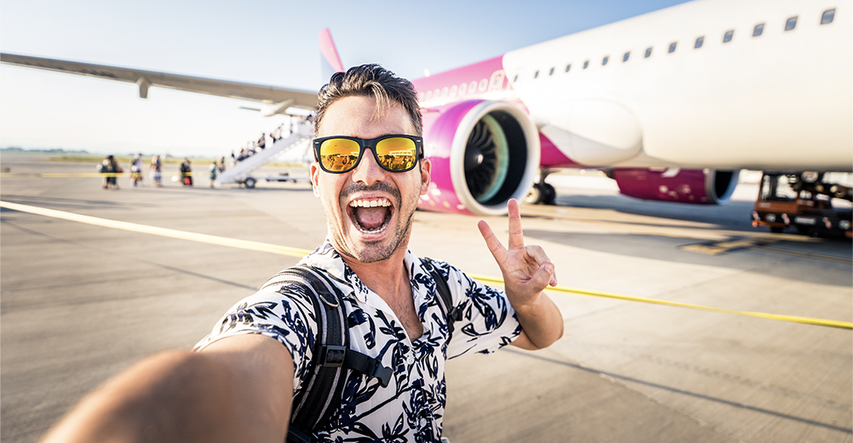 Happy young man taking selfie in front of airplane