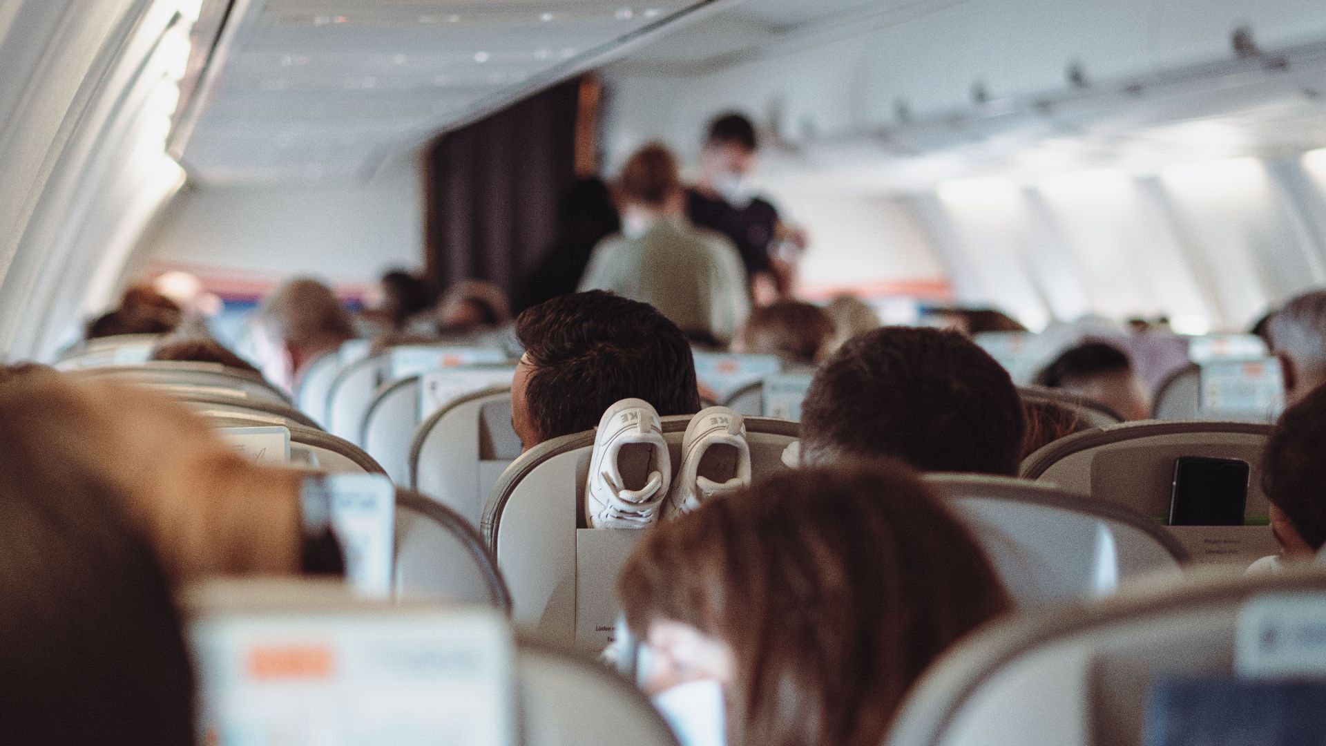 View of passengers wearing masks and seated in economy class during flight.