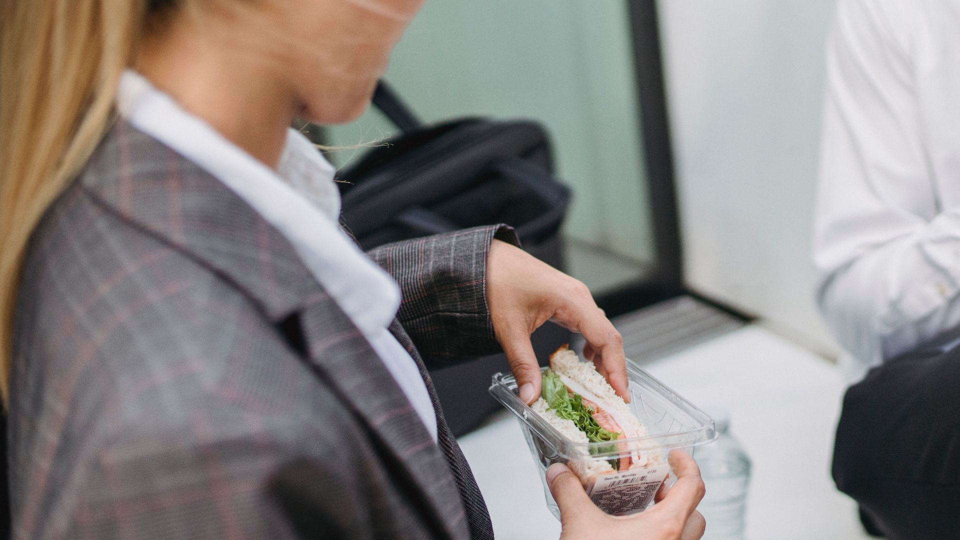 Two professionals in business attire enjoy sandwiches during a lunch break. Perfect for office and lifestyle themes.