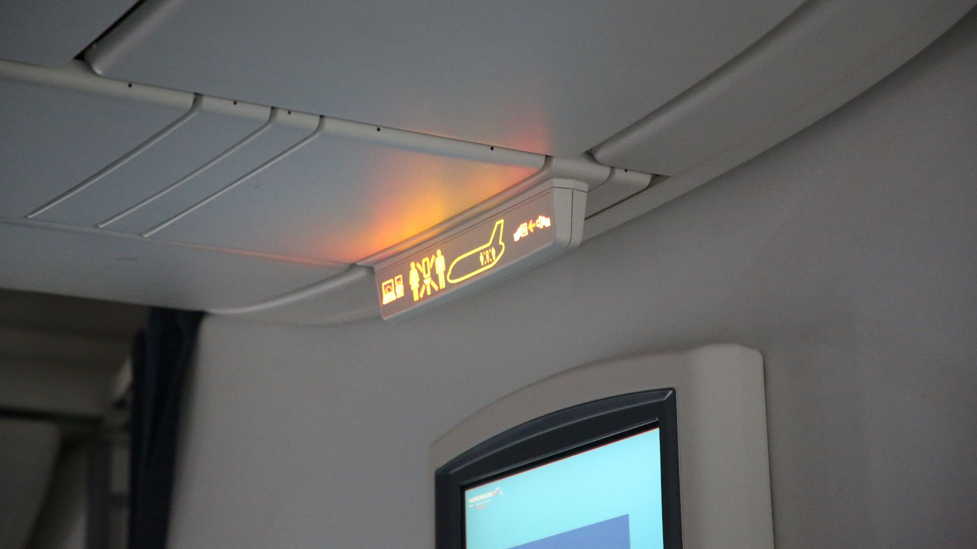 Central overhead bin and information sign in a widebody airliner