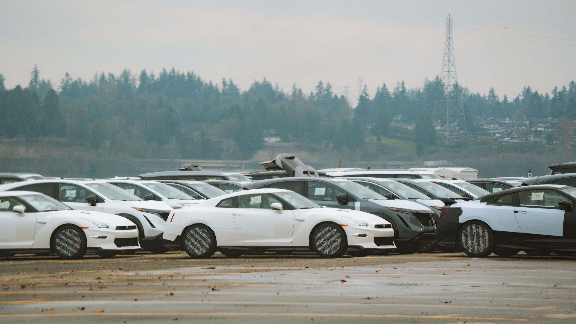 Wide shot of multiple sports cars parked outdoors on a cloudy day.