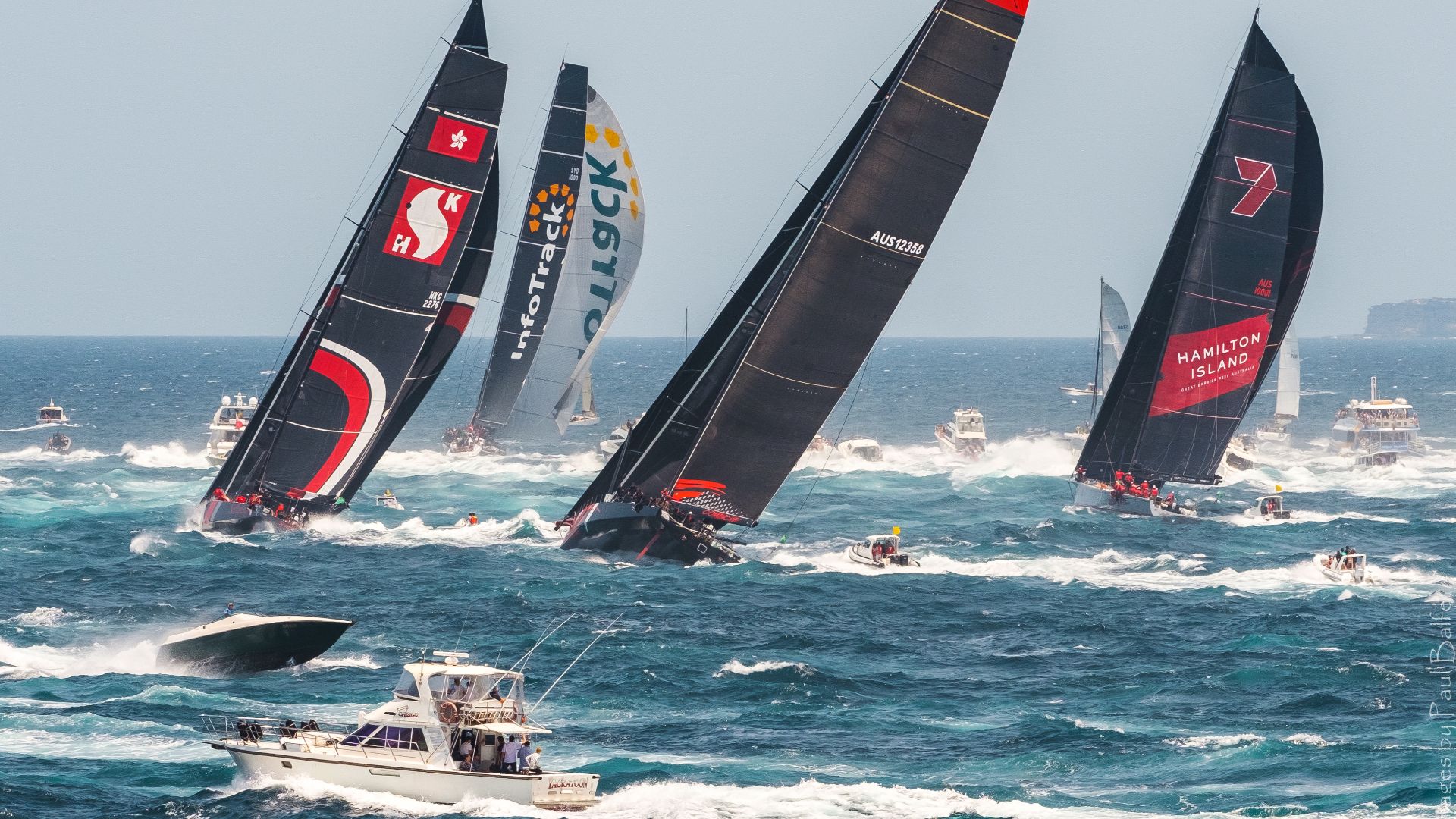 InfoTrack leads the fleet through Sydney Heads and south to Hobart in ideal, if smoky, conditions at the start of the 75th Sydney to Hobart Yacht Race.