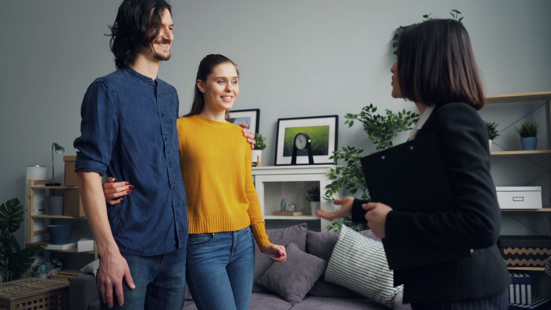 Young couple meeting with a real estate agent in a stylish indoor setting, discussing house options.